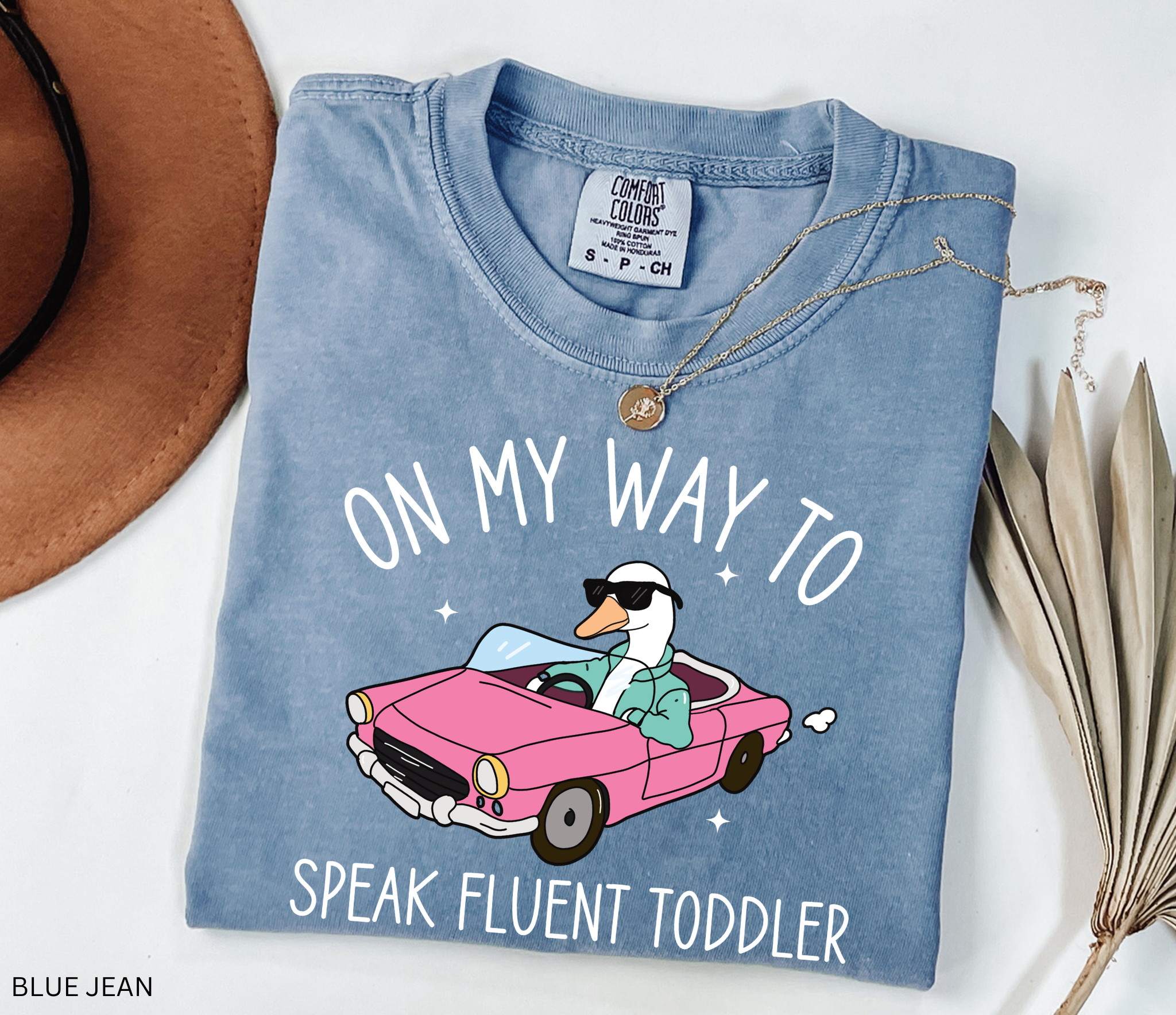 Daycare teacher shirt with a goose driving a pink convertible wearing sunglasses and the phrase ‘On My Way to Speak Fluent Toddler.