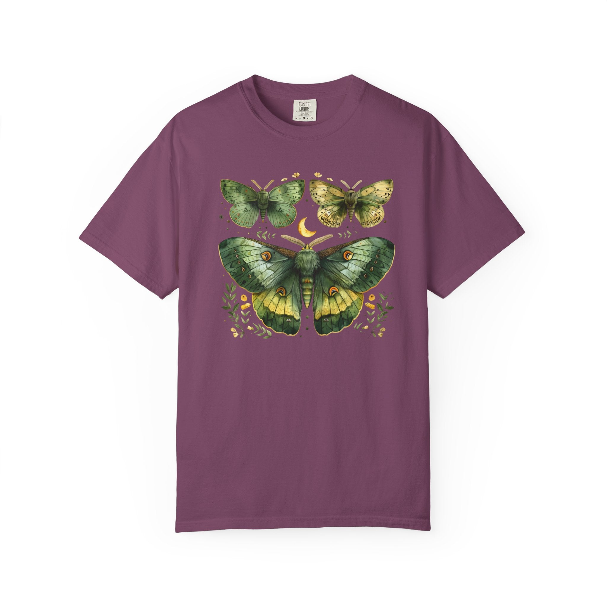 A purple short-sleeve crewneck t-shirt featuring a detailed graphic print of three green and yellow moths and butterflies with a small crescent moon and floral details on the chest, displayed against a plain white background.