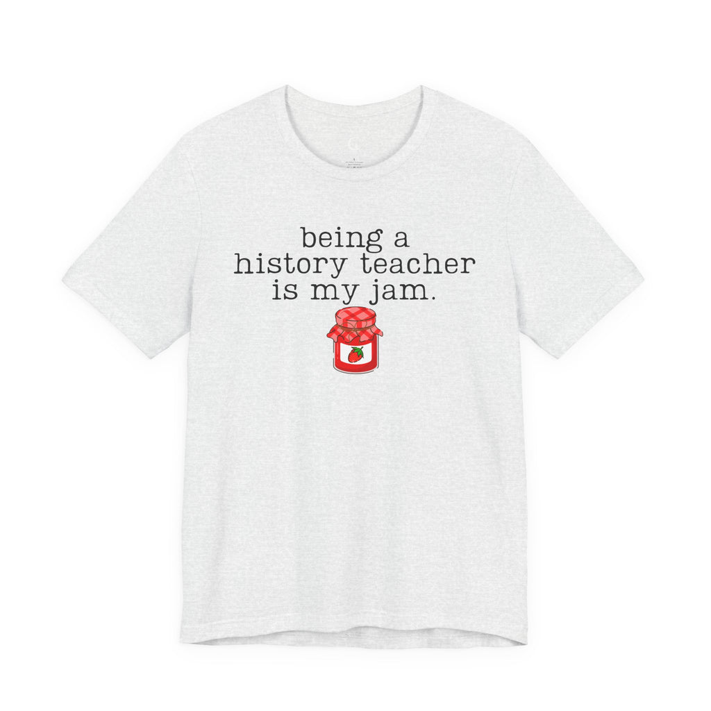 A white short-sleeve crewneck t-shirt with a graphic print that reads 'being a history teacher is my jam.' in black typewriter-style text above a small red jar illustration, shown on a plain white background.
