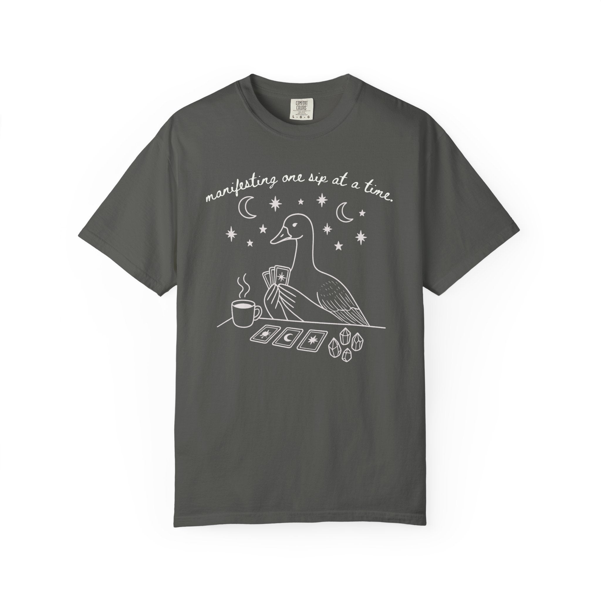 Comfort Colors t-shirt featuring a white tarot goose graphic with coffee, crystals, tarot cards, and the phrase "Manifesting One Sip at a Time."