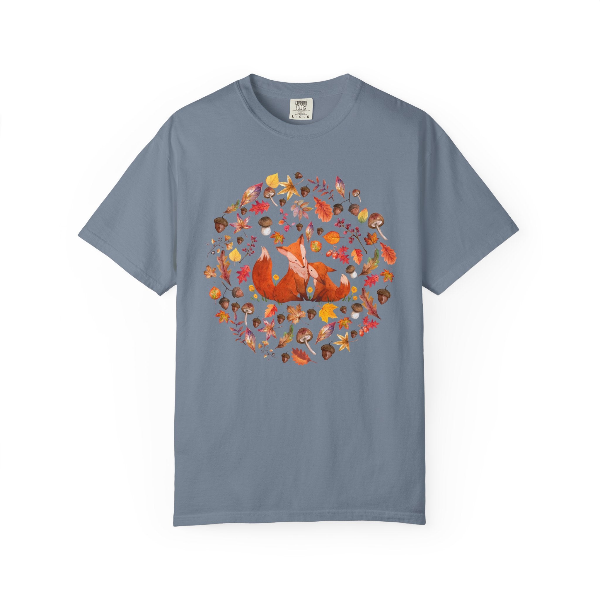 Comfort Colors ivory cottagecore shirt featuring two woodland foxes surrounded by autumn leaves, acorns, mushrooms, and forest botanicals in a whimsical watercolor style.