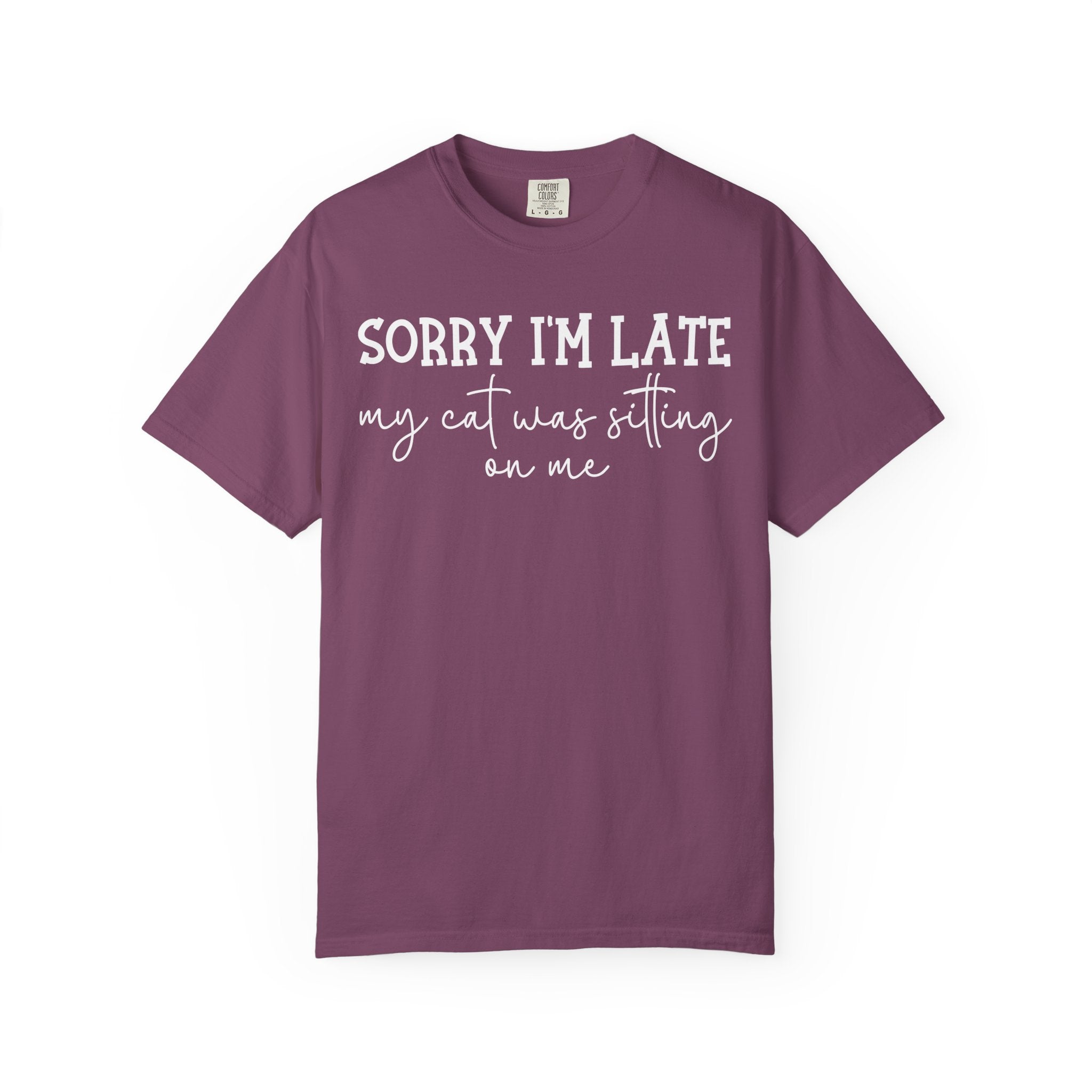 Funny cat lover graphic t-shirt featuring the quote "Sorry I'm Late My Cat Was Sitting on Me." A humorous gift for cat moms, cat dads, and anyone owned by a sleepy cat.