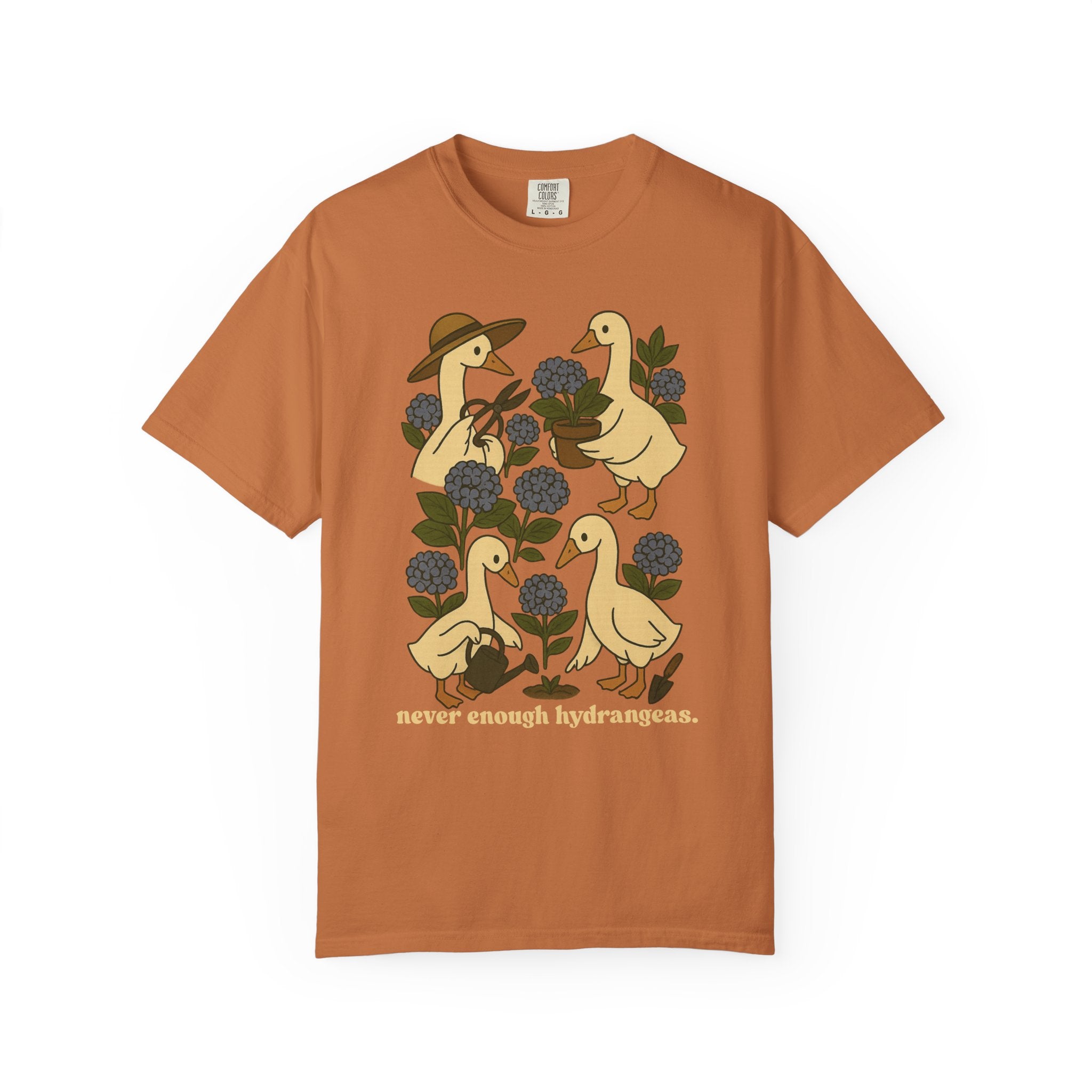 Illustration of four geese gardening among blue hydrangeas with text “never enough hydrangeas.” Cottagecore garden shirt design.