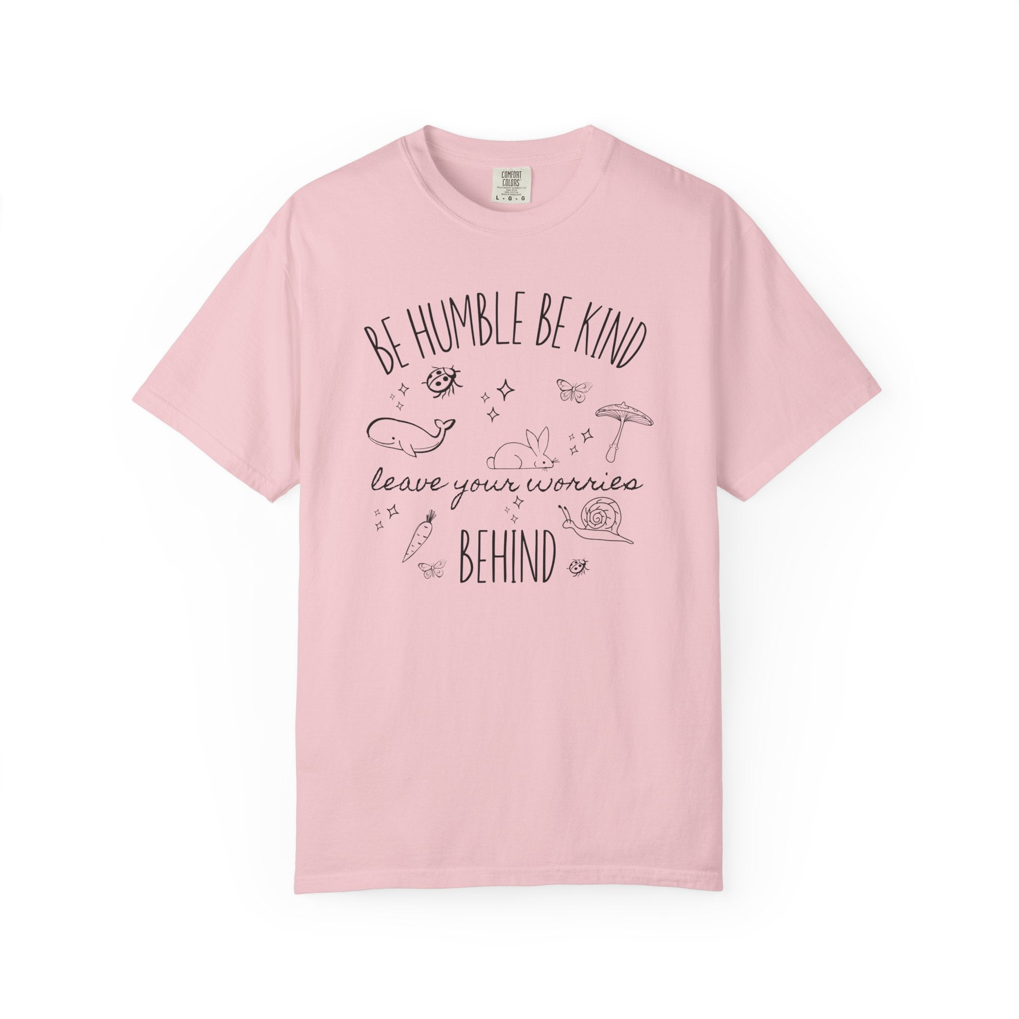 Comfort Colors shirt featuring the quote "Be Humble Be Kind Leave Your Worries Behind" surrounded by whimsical illustrations including a rabbit, whale, mushroom, snail, butterflies, and ladybugs in a cottagecore style.