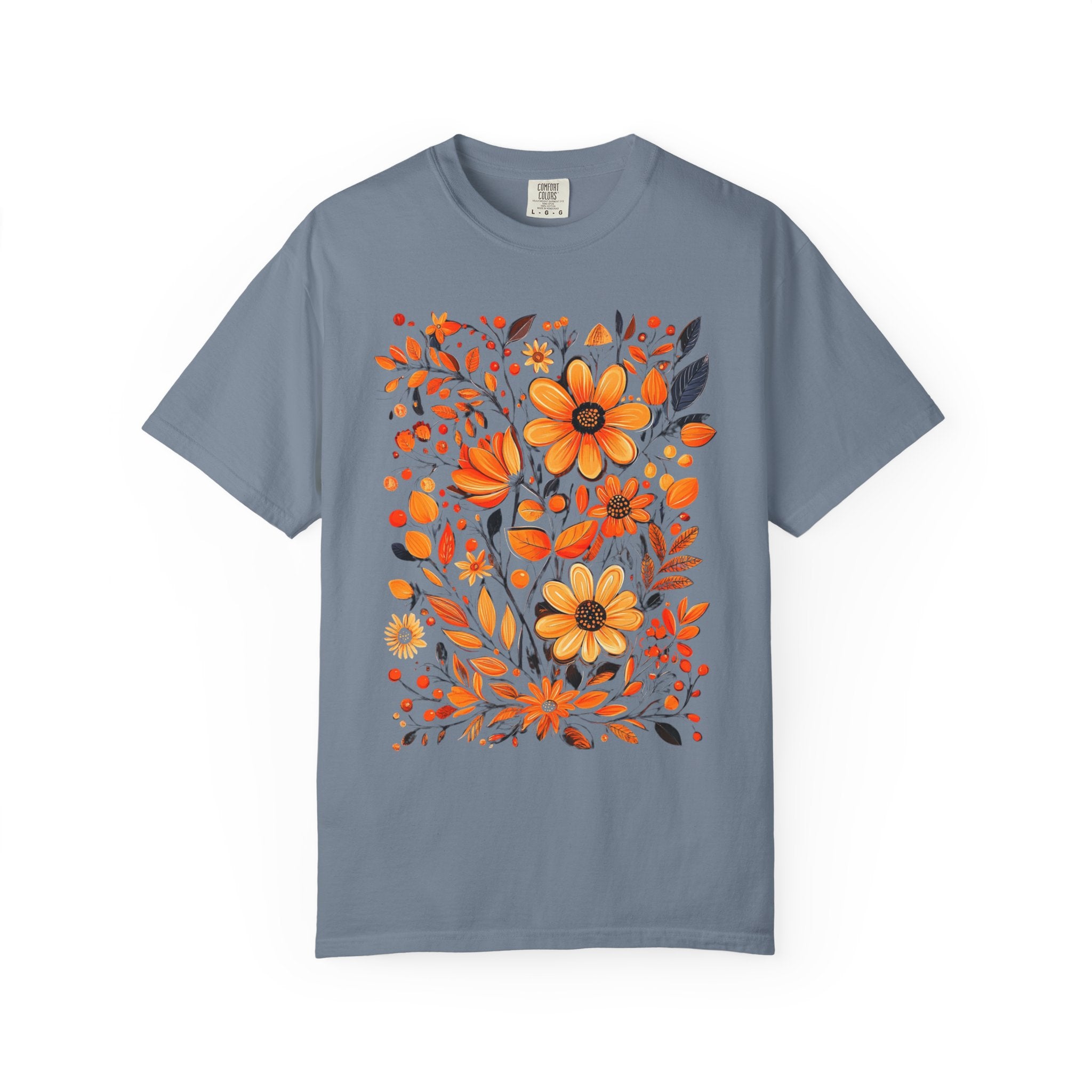 A hand-painted style floral design featuring orange and gold flowers with dark leaves, printed on a Comfort Colors cottagecore shirt.