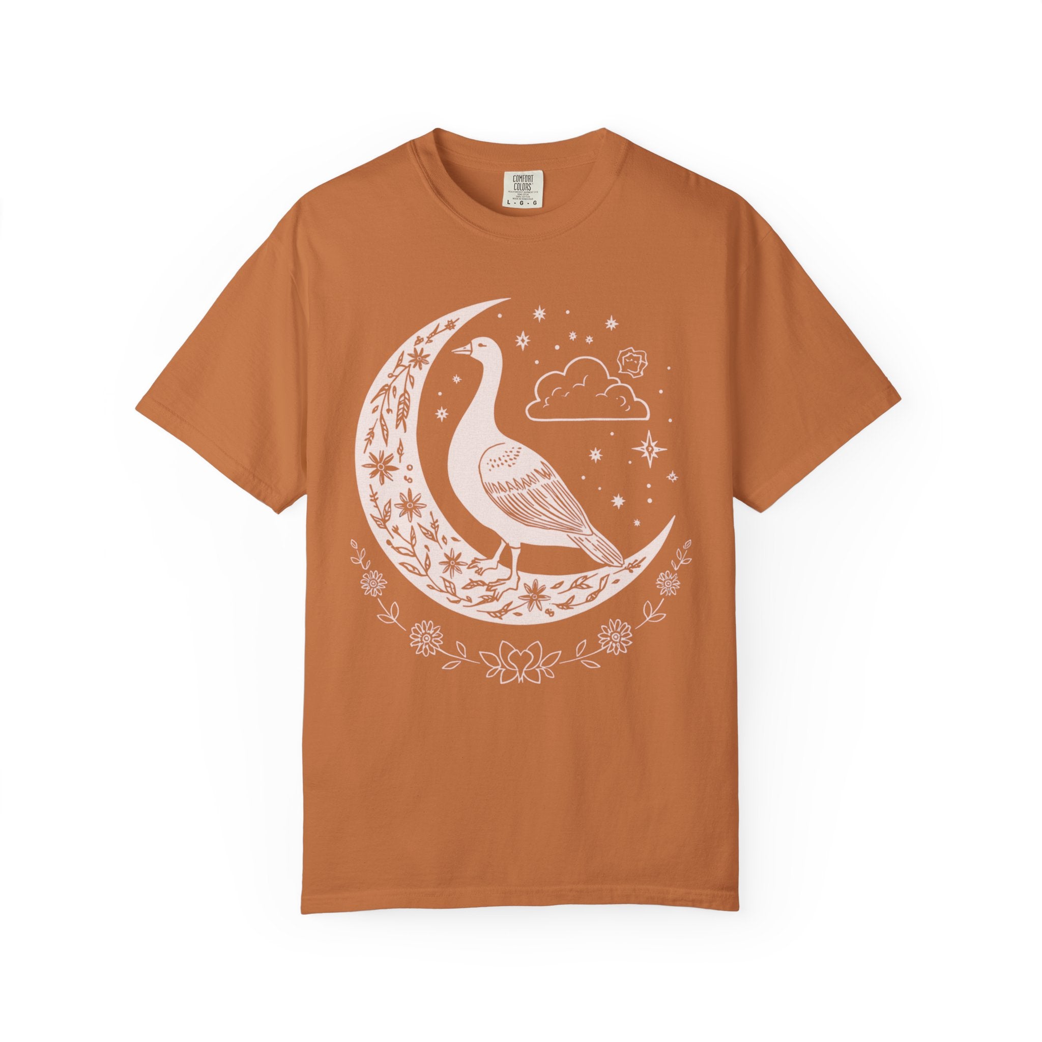 Celestial goose shirt featuring a whimsical goose on a crescent moon with stars, clouds, and floral details — witchy cottagecore design.