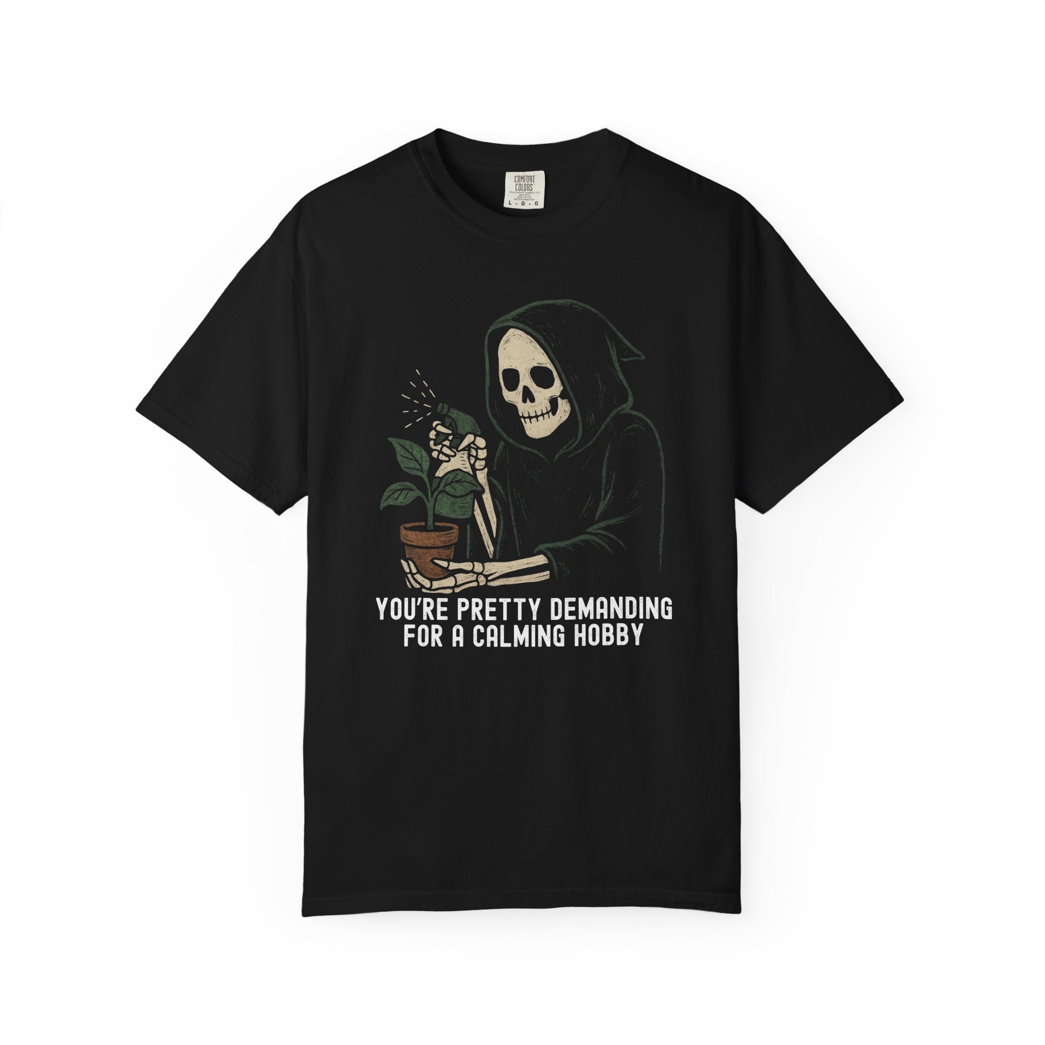 Halloween-style shirt featuring a grim reaper skeleton watering a potted plant with the phrase “You’re Pretty Demanding for a Calming Hobby.”