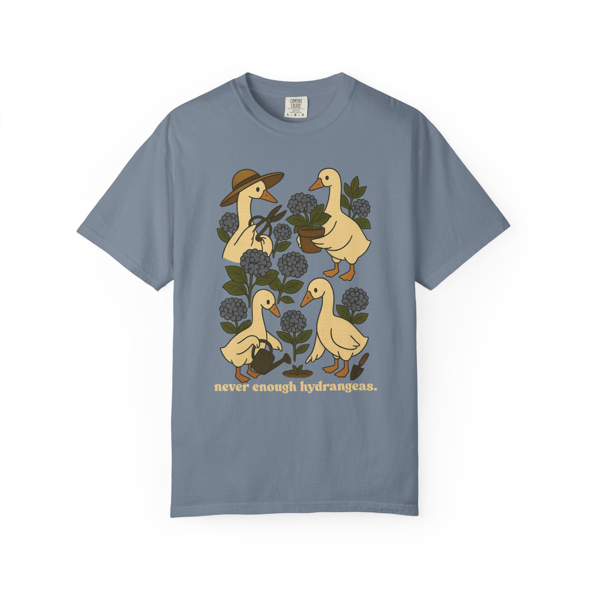 Illustration of four geese gardening among blue hydrangeas with text “never enough hydrangeas.” Cottagecore garden shirt design.
