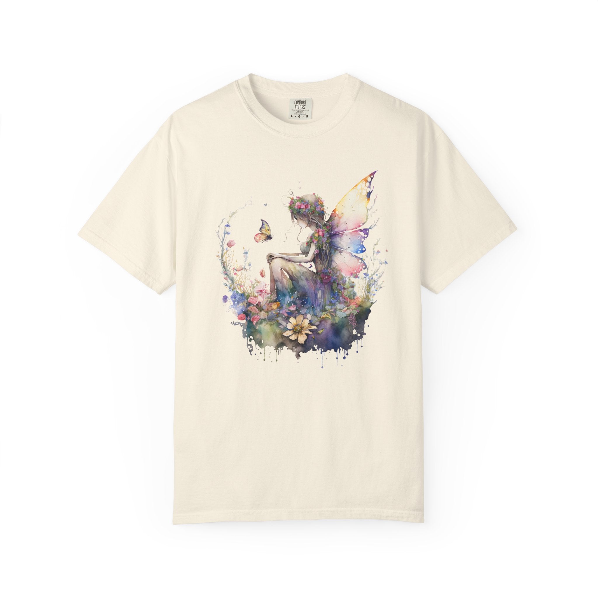 An off-white short-sleeve crewneck t-shirt featuring a colorful watercolor graphic of a fairy sitting among flowers, displayed against a solid white background.