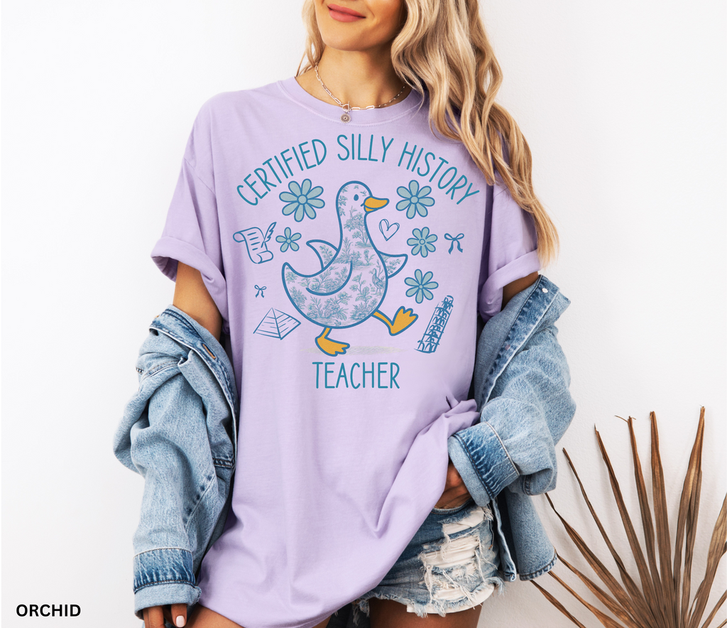 Funny history teacher shirt with a patterned goose surrounded by flowers, bows, and history doodles. Reads ‘Certified Silly History Teacher.’ Perfect classroom tee