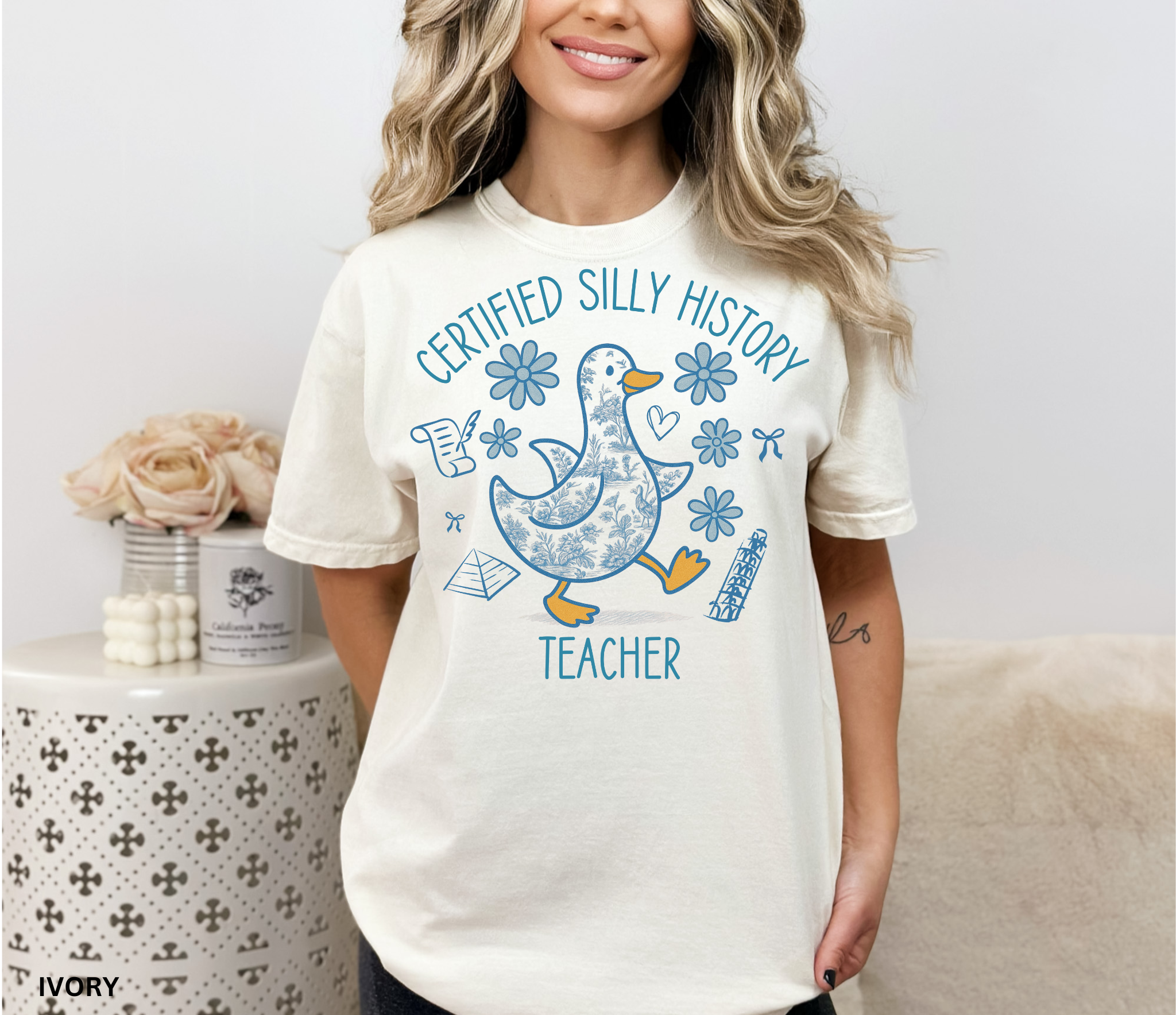 Funny history teacher shirt with a patterned goose surrounded by flowers, bows, and history doodles. Reads ‘Certified Silly History Teacher.’ Perfect classroom tee