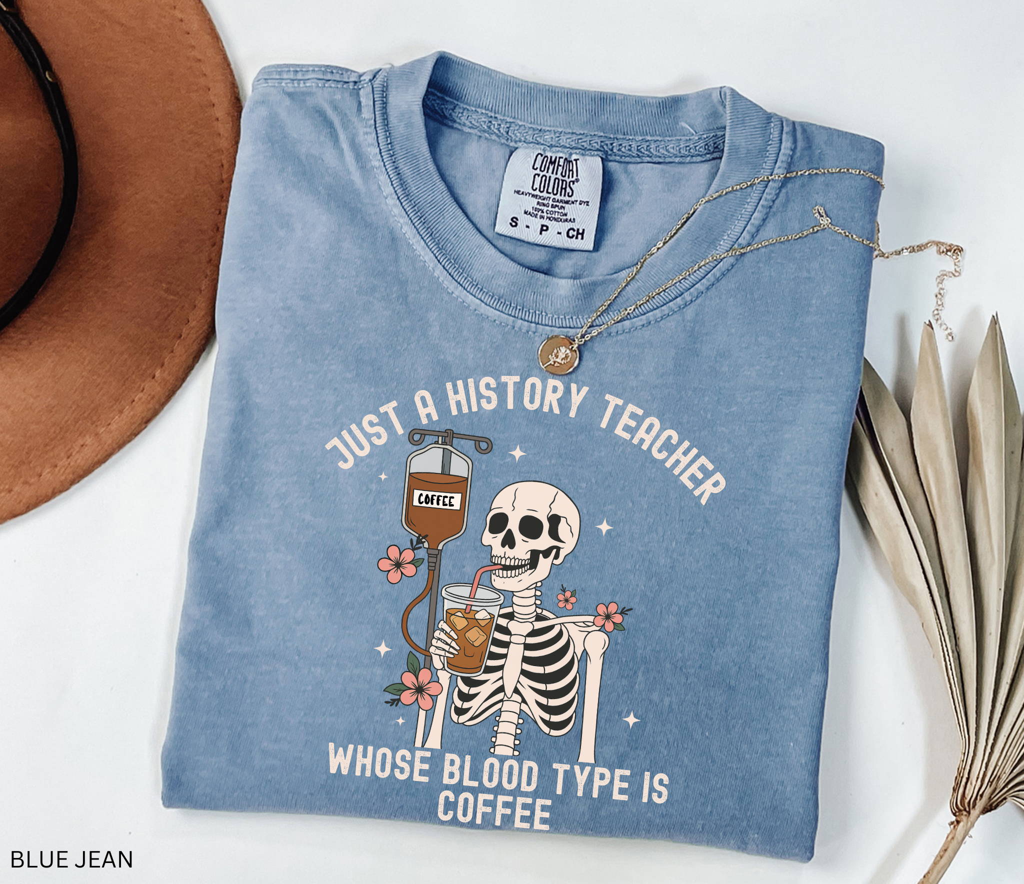 Halloween skeleton shirt with skeleton sipping iced coffee through a straw connected to a coffee IV drip, decorated with flowers. Funny spooky coffee lover tee