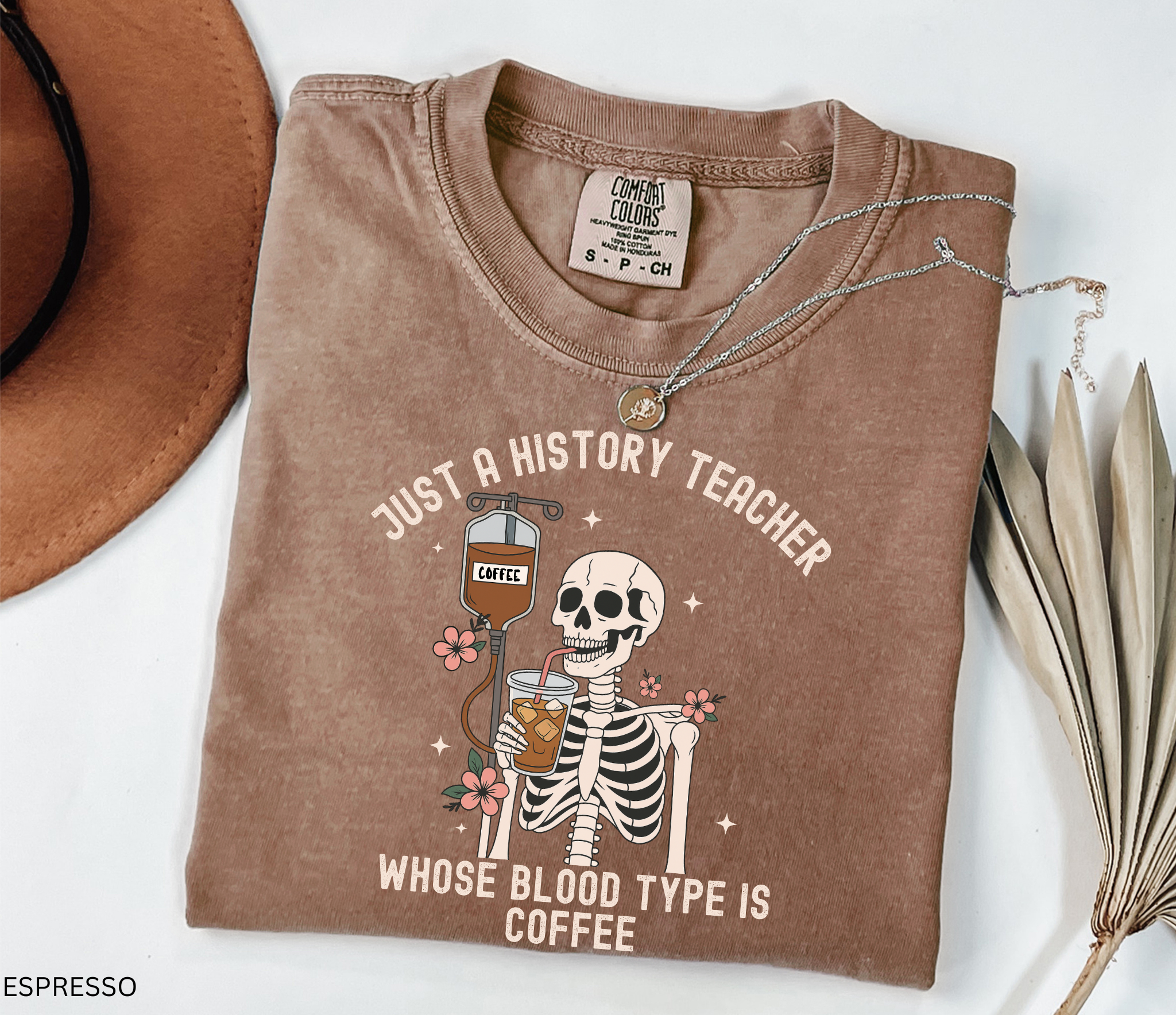 Halloween skeleton shirt with skeleton sipping iced coffee through a straw connected to a coffee IV drip, decorated with flowers. Funny spooky coffee lover tee