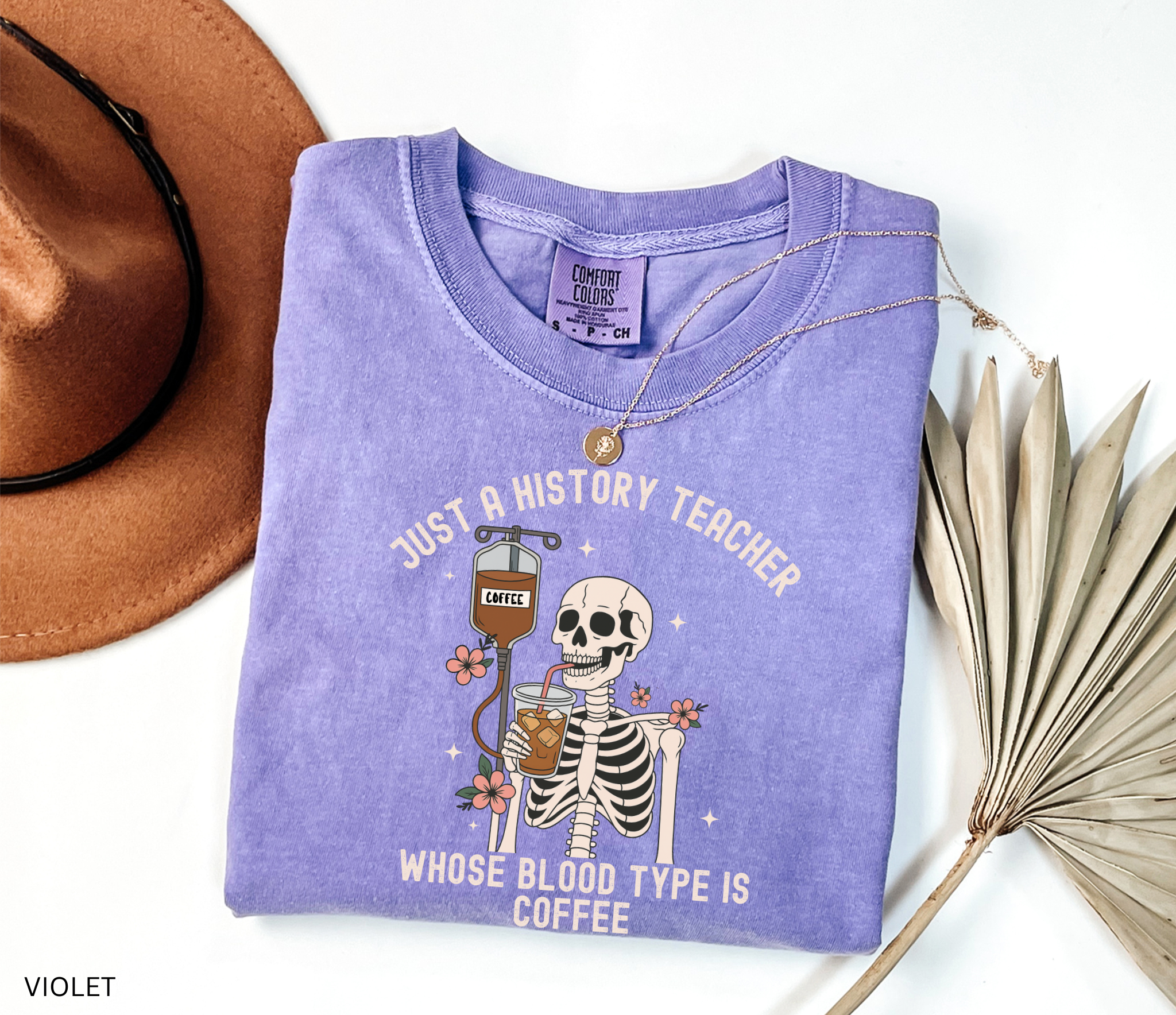 Halloween skeleton shirt with skeleton sipping iced coffee through a straw connected to a coffee IV drip, decorated with flowers. Funny spooky coffee lover tee