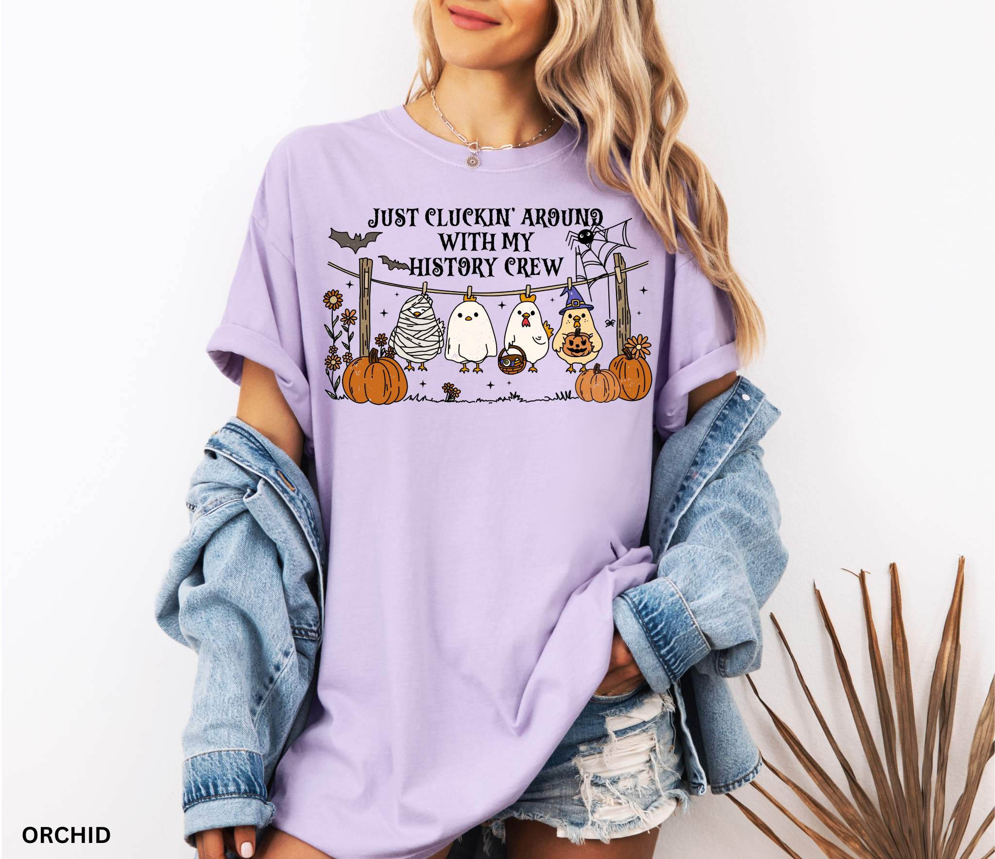 Halloween history teacher shirt with four cartoon chickens dressed in costumes (mummy, ghost, witch, and trick-or-treater) standing on a clothesline with pumpkins and bats, designed as a funny teacher Halloween graphic tee.