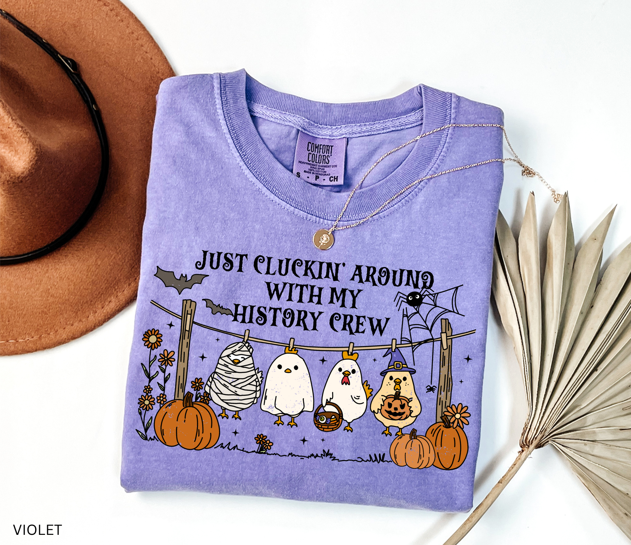 Halloween history teacher shirt with four cartoon chickens dressed in costumes (mummy, ghost, witch, and trick-or-treater) standing on a clothesline with pumpkins and bats, designed as a funny teacher Halloween graphic tee.