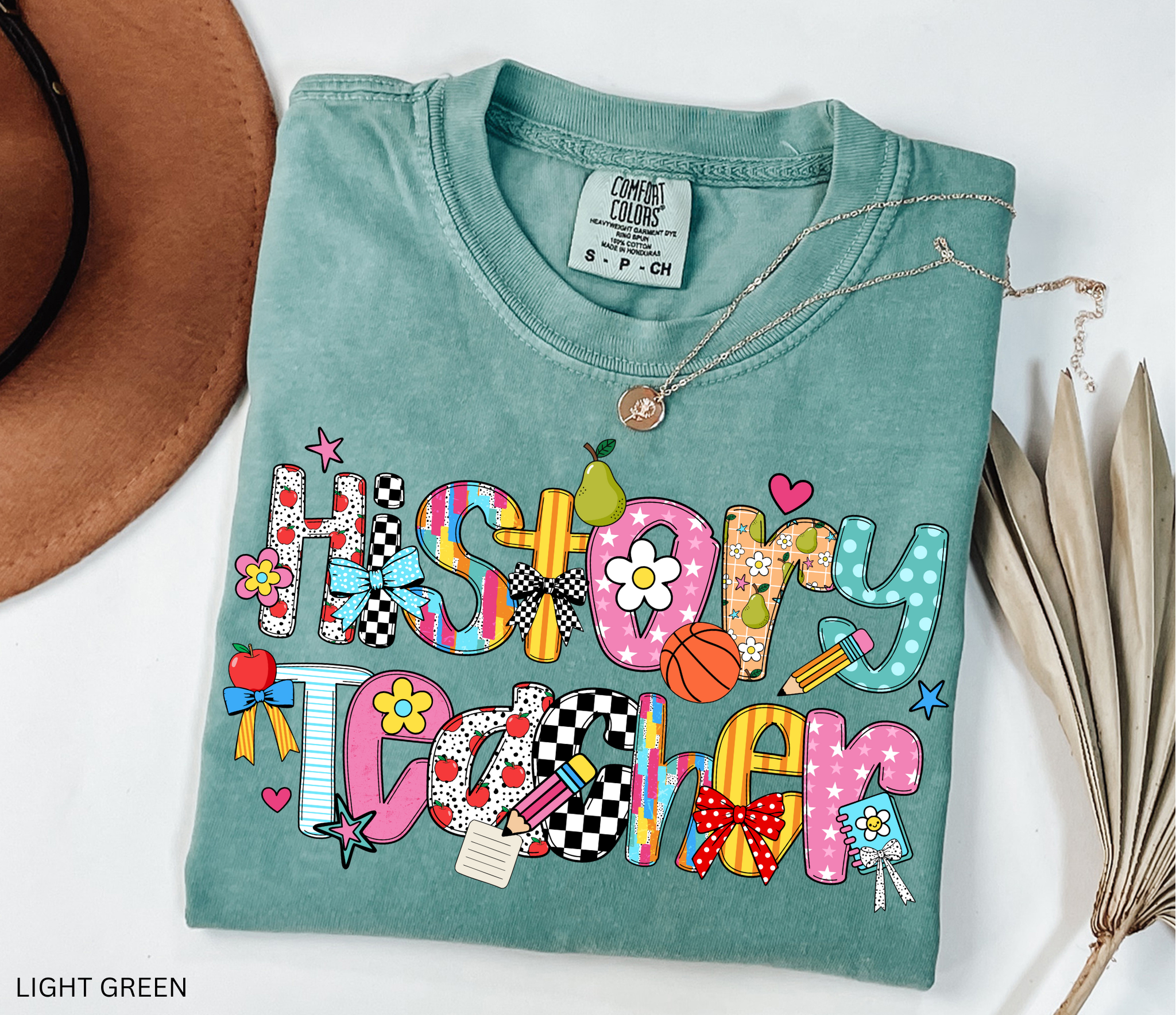 Bright and colorful shirt design with the words “History Teacher” in patchwork-style letters decorated with apples, pencils, bows, flowers, hearts, and stars. Perfect gift for teachers.