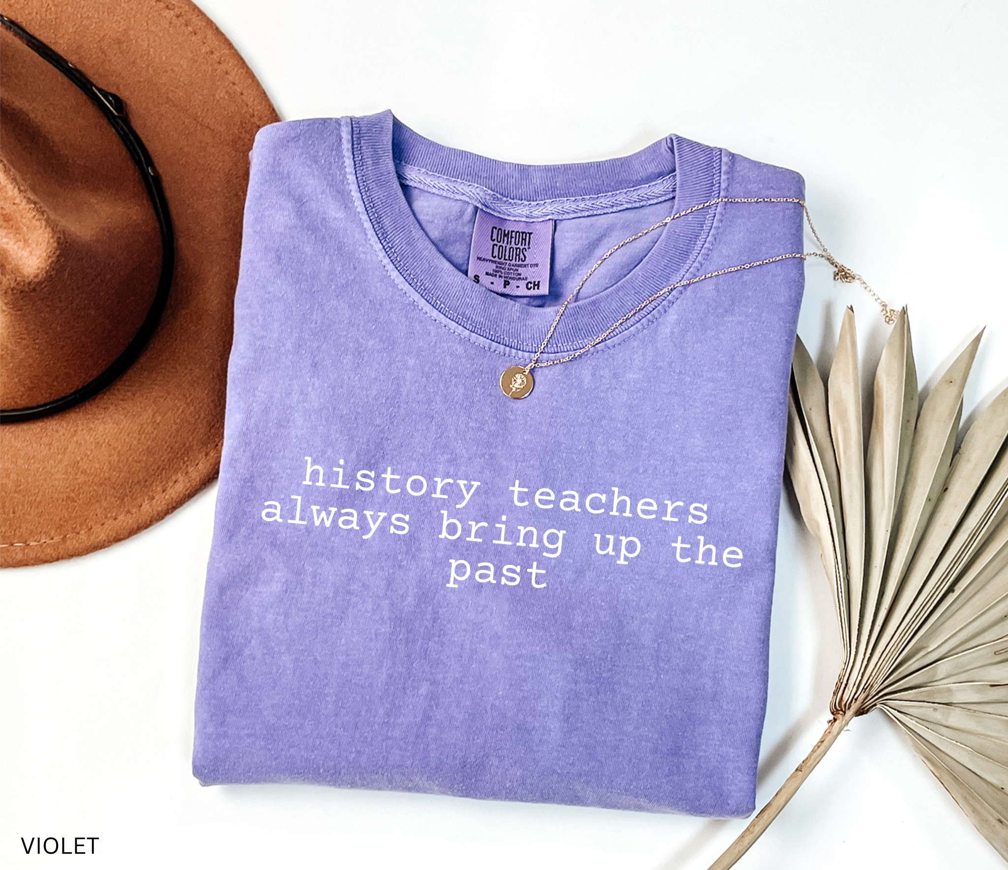 Black t-shirt design with the phrase “history teachers always bring up the past” in bold white typewriter-style font, a funny gift for history teachers.