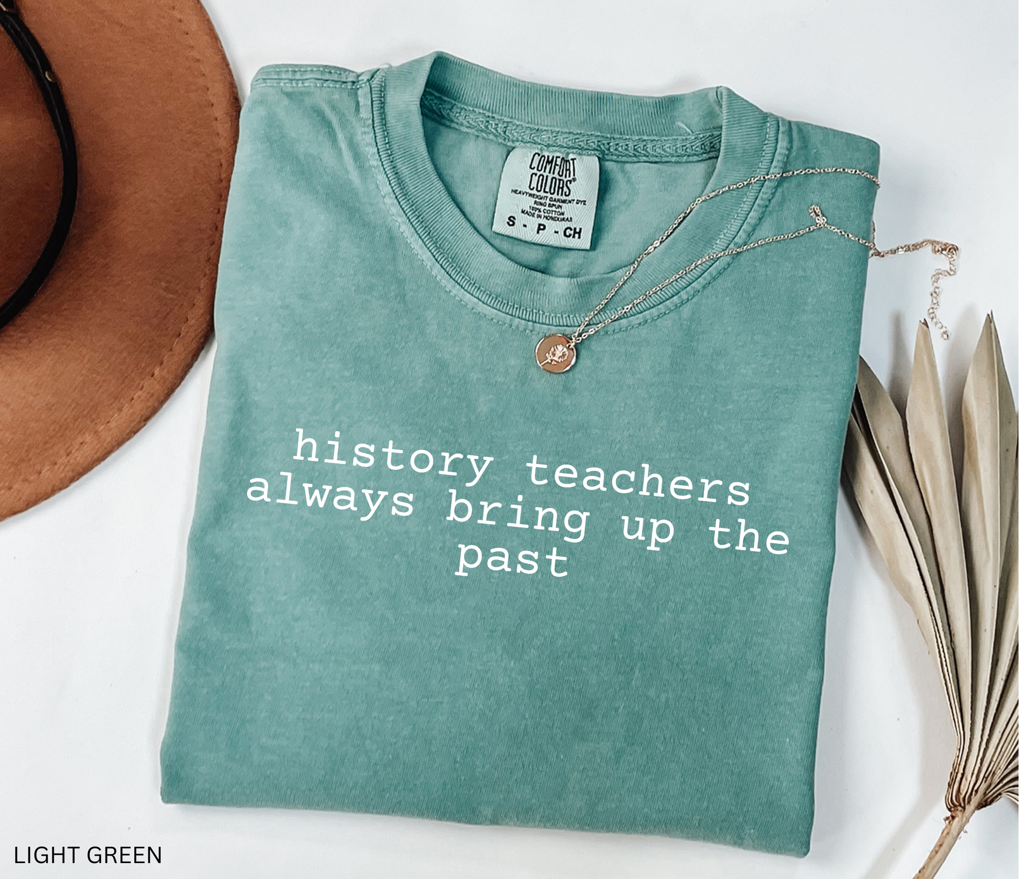 Black t-shirt design with the phrase “history teachers always bring up the past” in bold white typewriter-style font, a funny gift for history teachers.