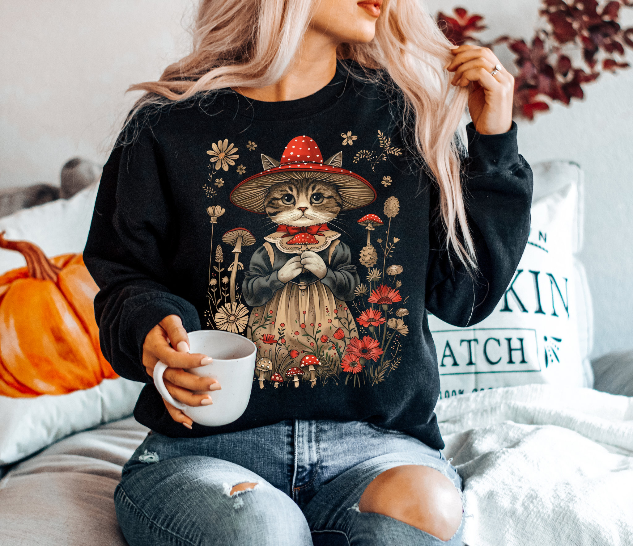 Cottagecore cat sweatshirt with whimsical cat in red mushroom witch hat and vintage dress surrounded by wildflowers and toadstools.