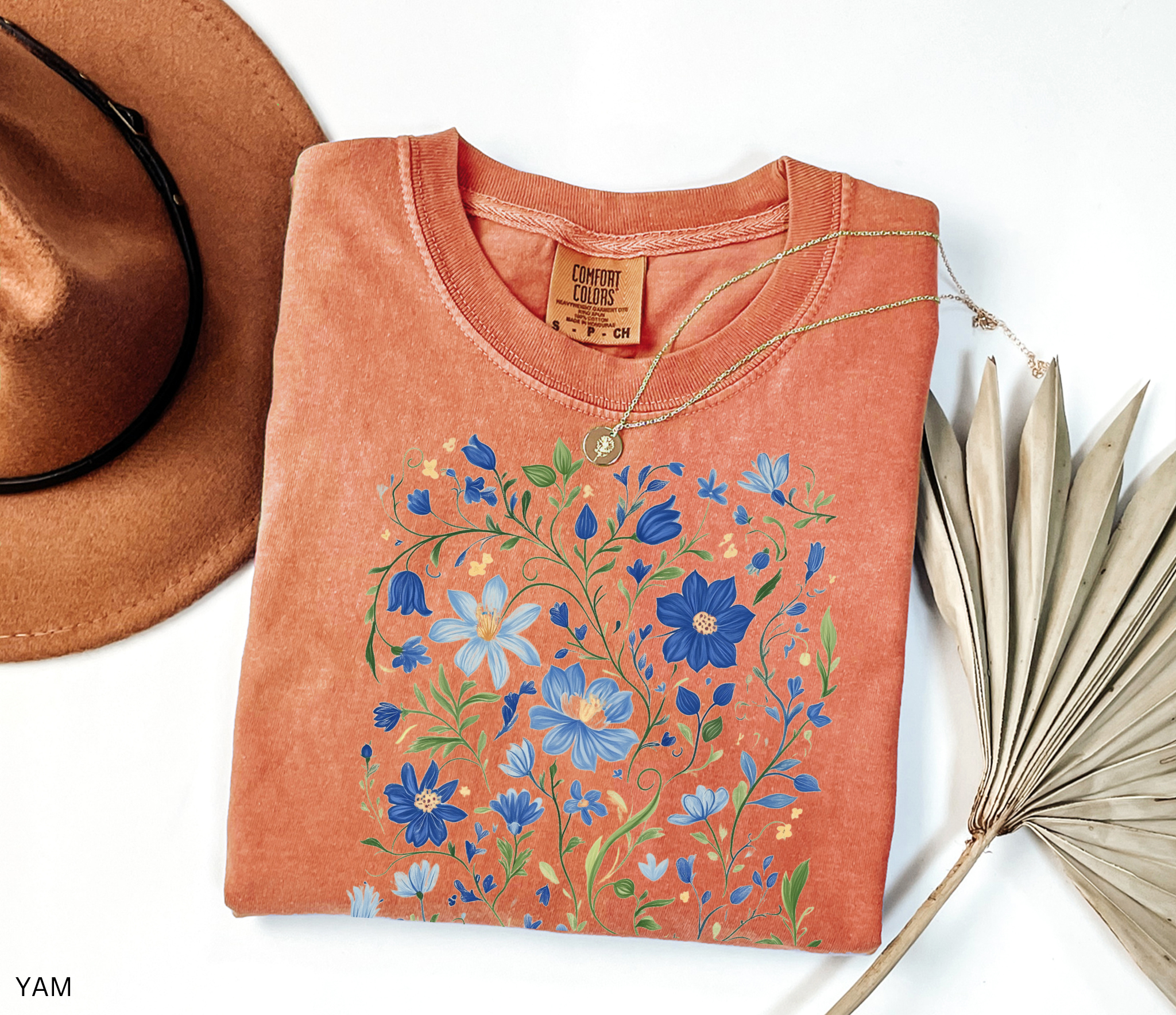 Detailed folk-art style design of blue wildflowers and green vines, printed on a cottagecore floral t-shirt.