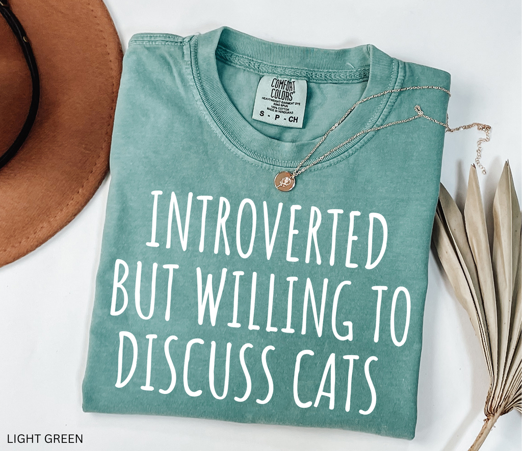 Funny Comfort Colors cat lover shirt featuring the phrase "Introverted But Willing to Discuss Cats," designed for introverts, cat moms, cat dads, and pet lovers.