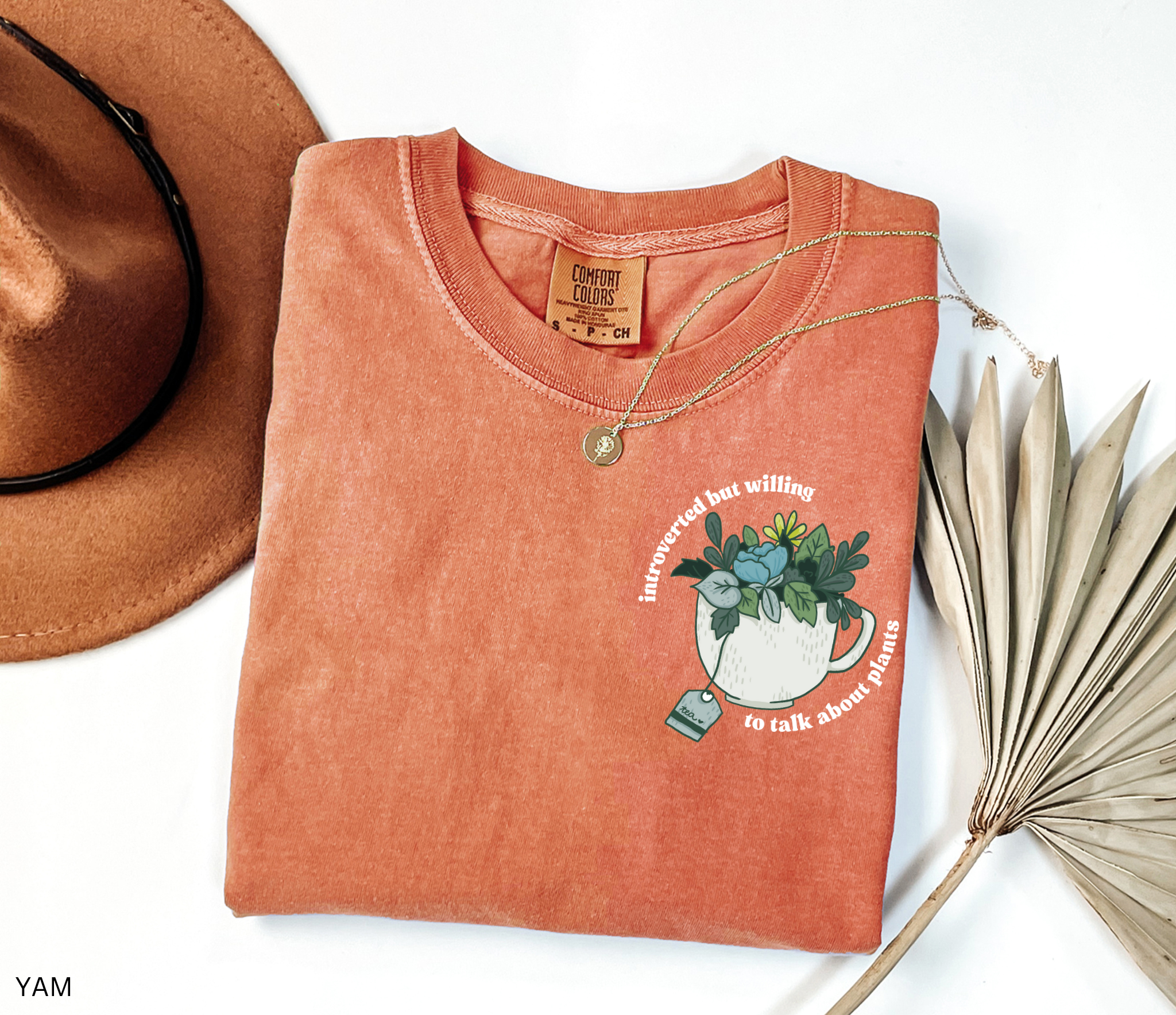 Illustrated cottagecore teacup filled with leafy green plants and flowers, with the phrase “introverted but willing to talk about plants” in curved lettering.