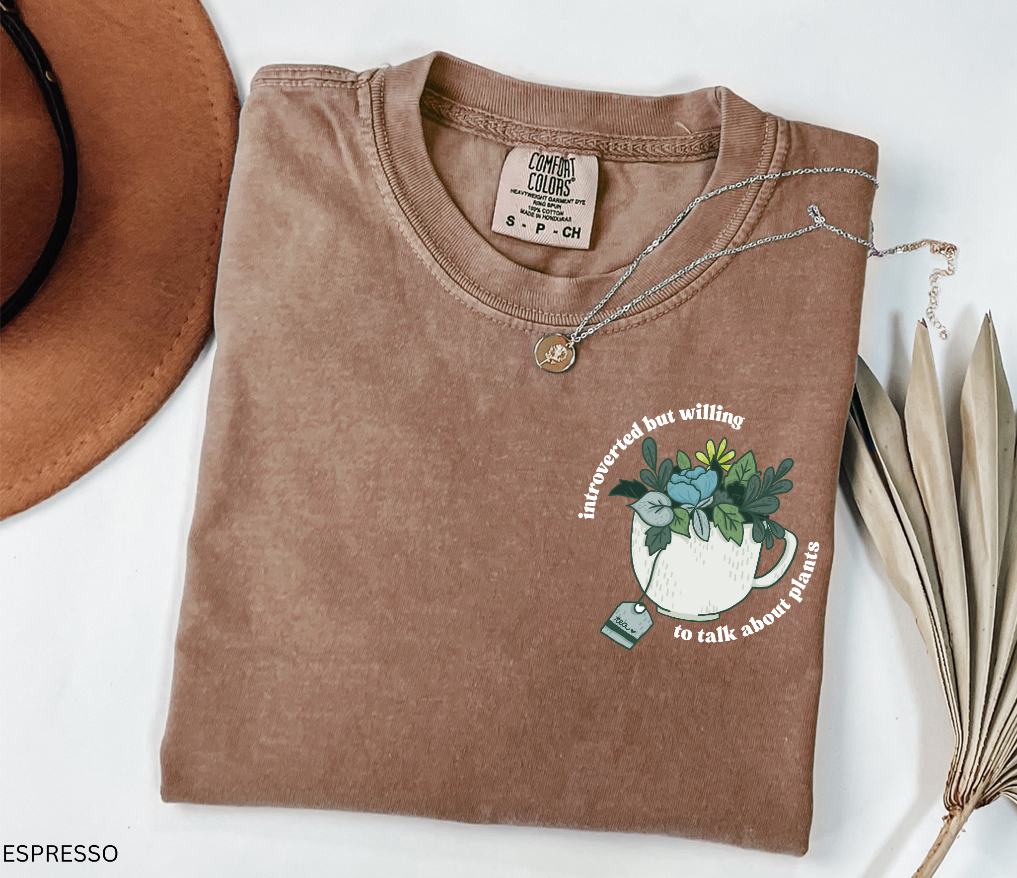 Illustrated cottagecore teacup filled with leafy green plants and flowers, with the phrase “introverted but willing to talk about plants” in curved lettering.