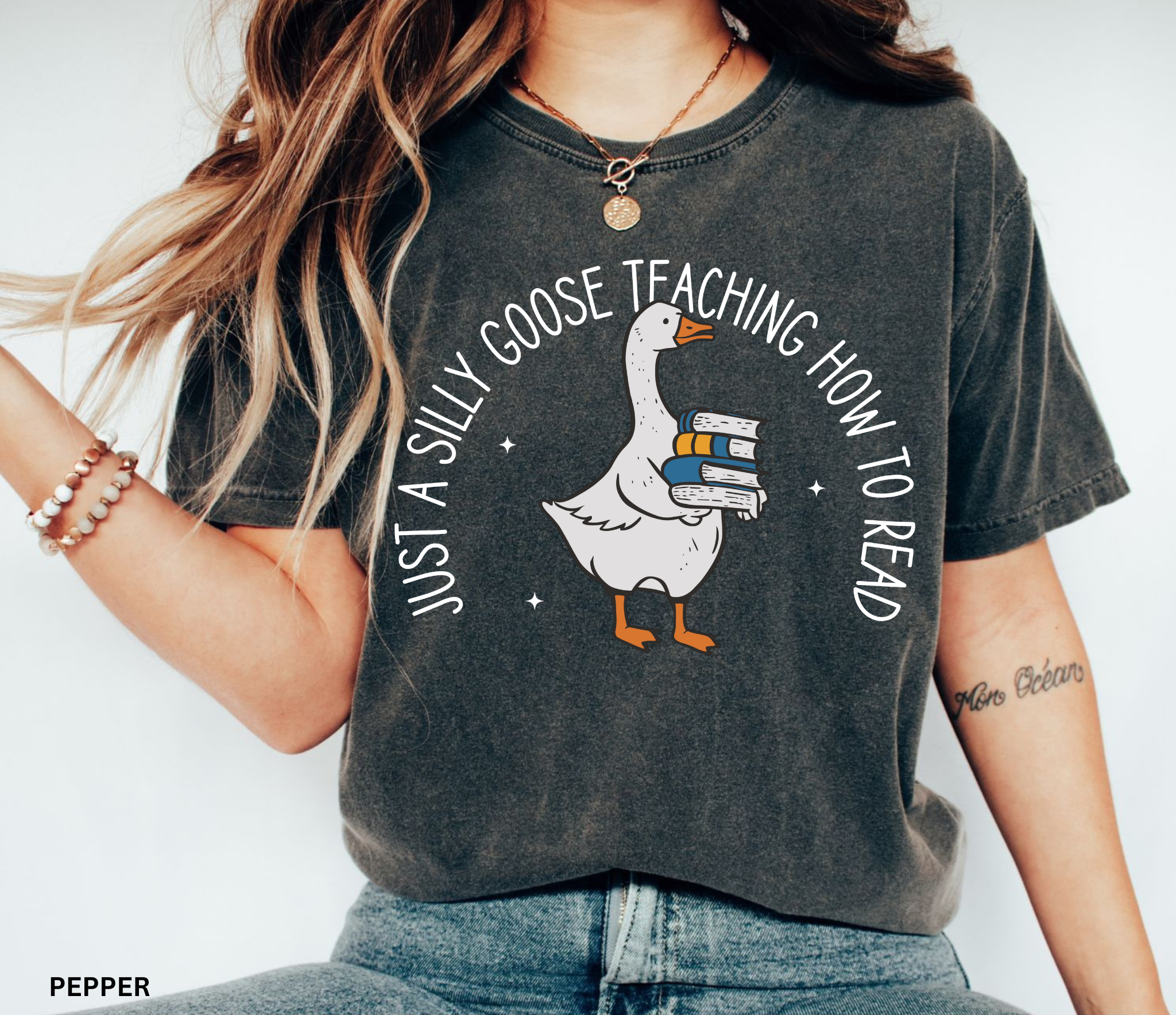 ust a Silly Goose Teaching How to Read text design featuring a cartoon goose holding a stack of books on a black background, created for English teachers.