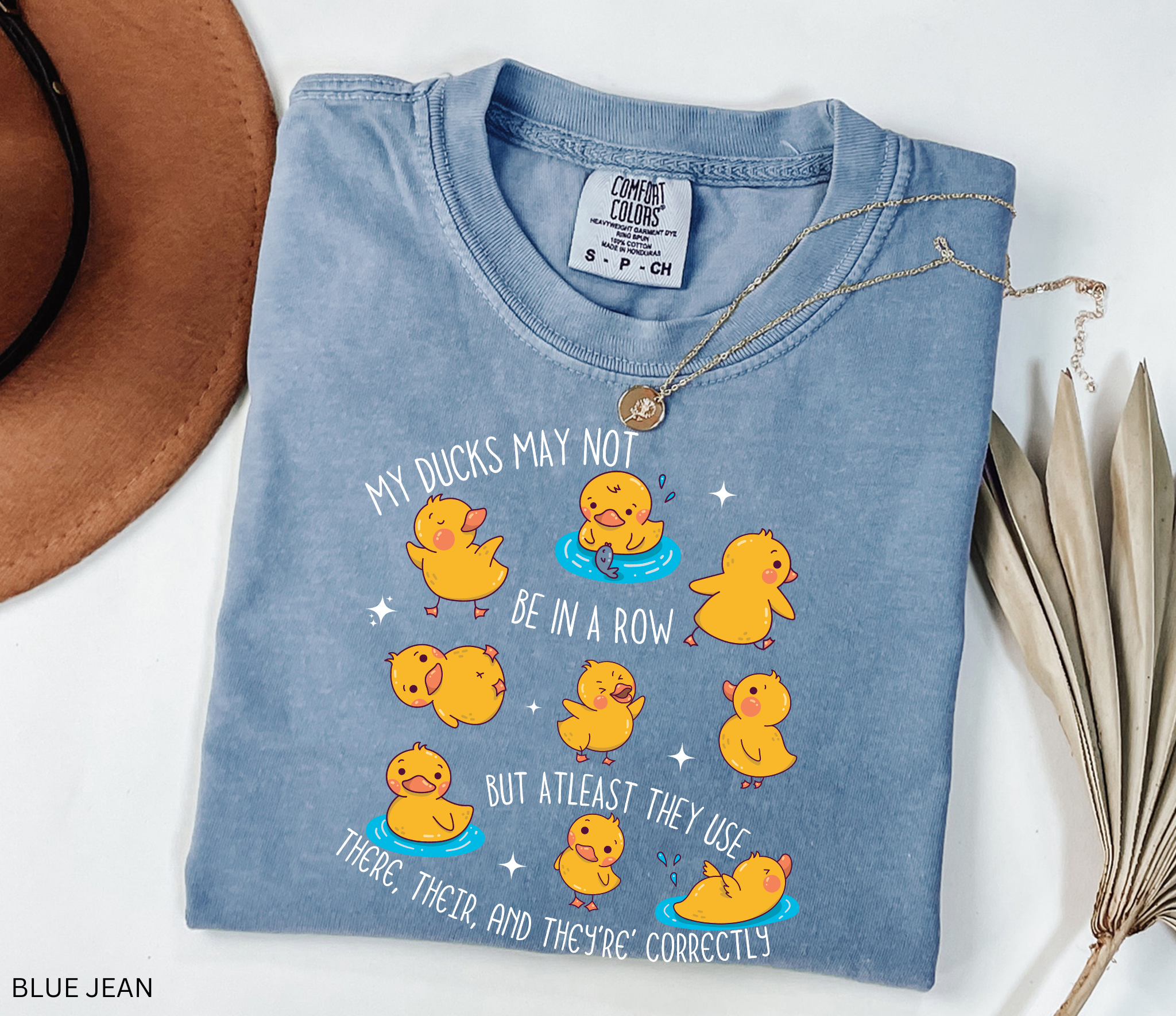 Playful duck illustration with the phrase ‘My ducks may not be in a row, but at least they use there, their, and they’re correctly,’ designed as a humorous shirt for English teachers.