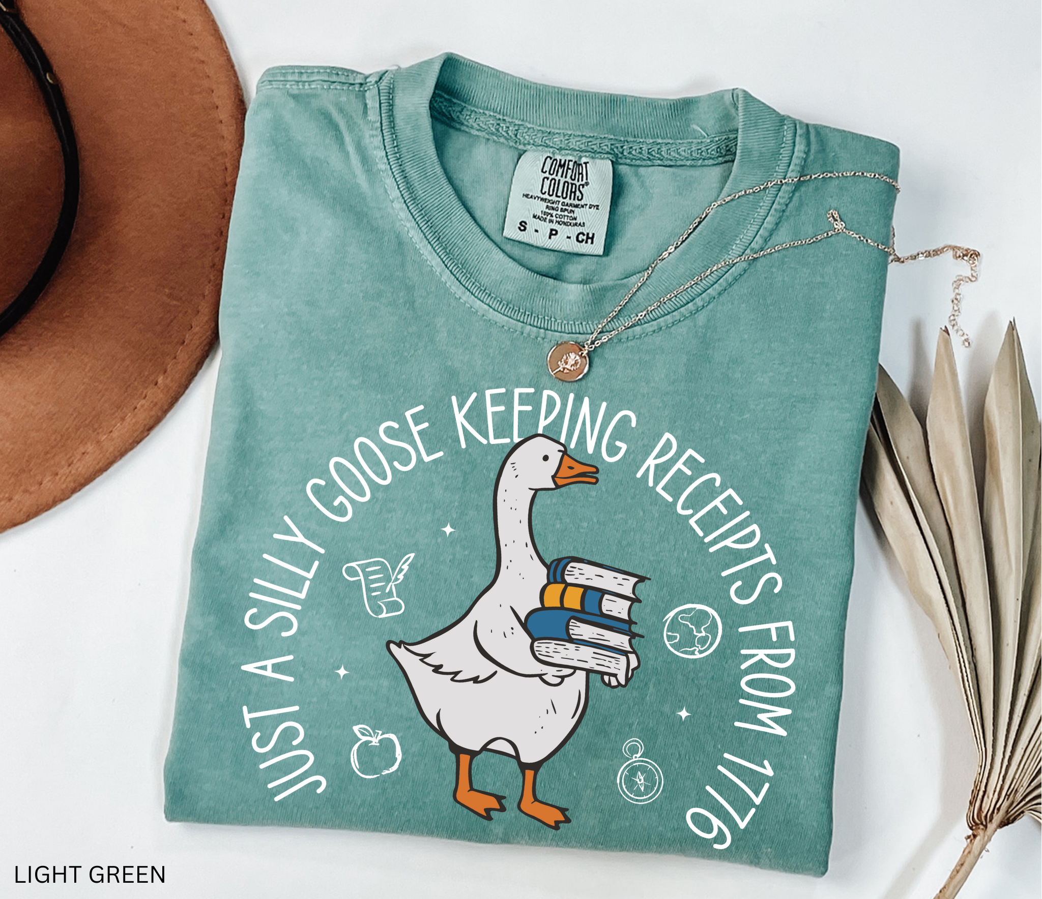 History teacher shirt with a goose holding books and the phrase ‘Just a Historical Goose Keeping Receipts from 1776.’ Funny teacher gift tee