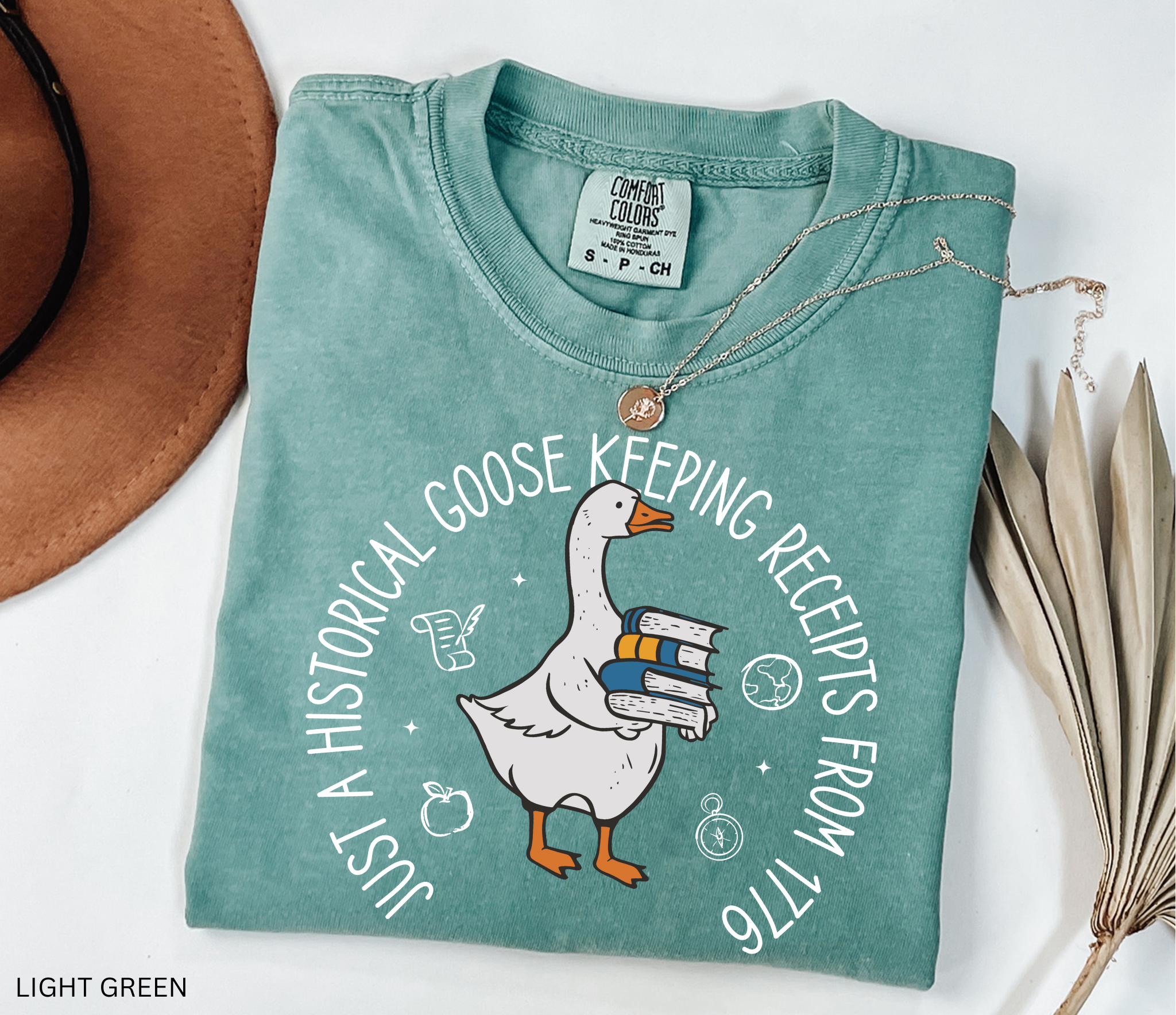 History teacher shirt with a goose holding books and the phrase ‘Just a Historical Goose Keeping Receipts from 1776.’ Funny teacher gift tee.