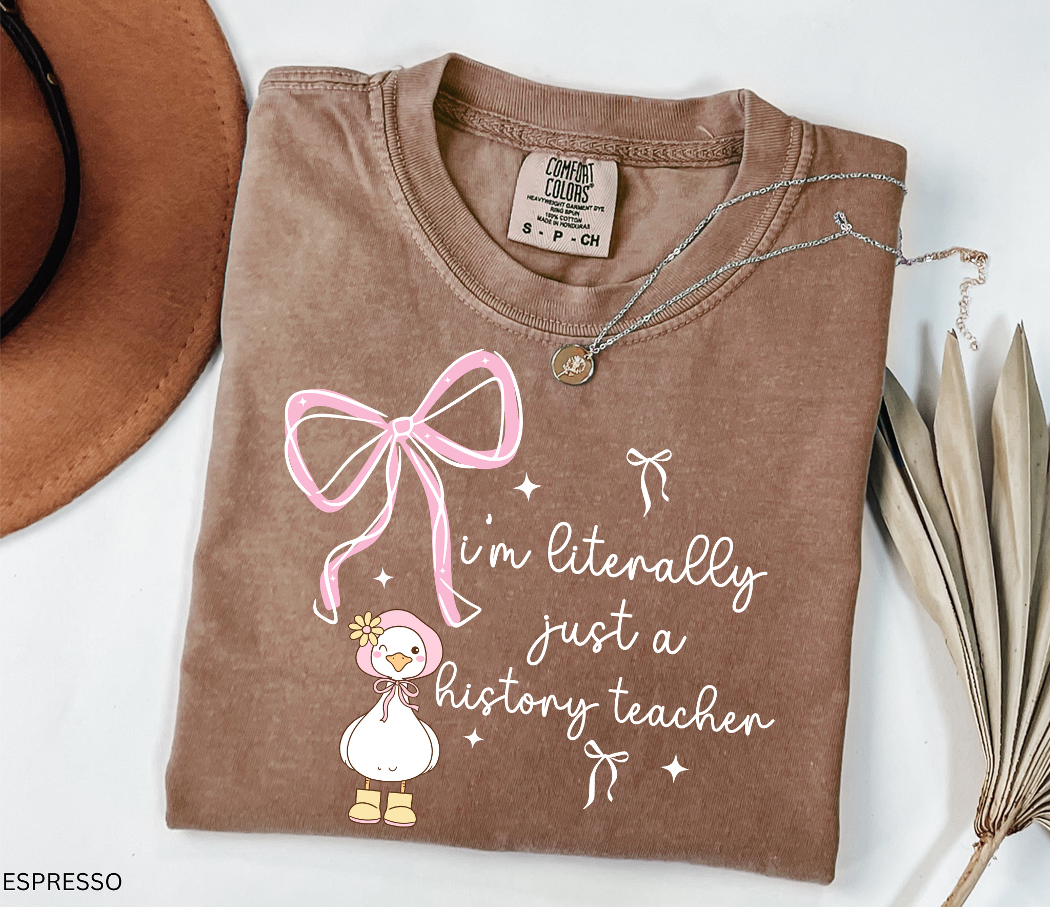 Funny history teacher shirt with a cute goose, pink bows, and the phrase ‘I’m literally just a history teacher.’ Coquette aesthetic social studies tee.