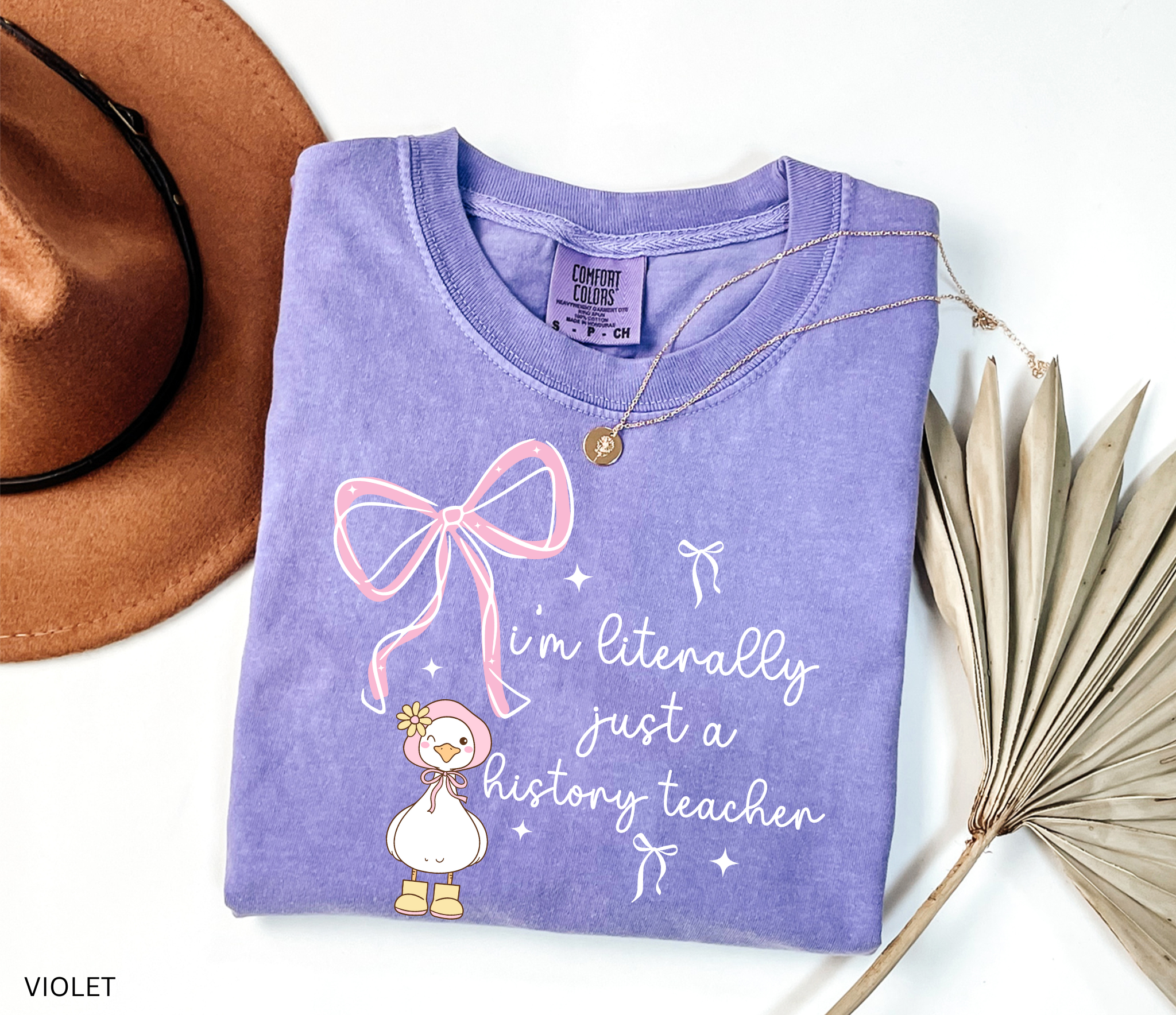 Funny history teacher shirt with a cute goose, pink bows, and the phrase ‘I’m literally just a history teacher.’ Coquette aesthetic social studies tee.