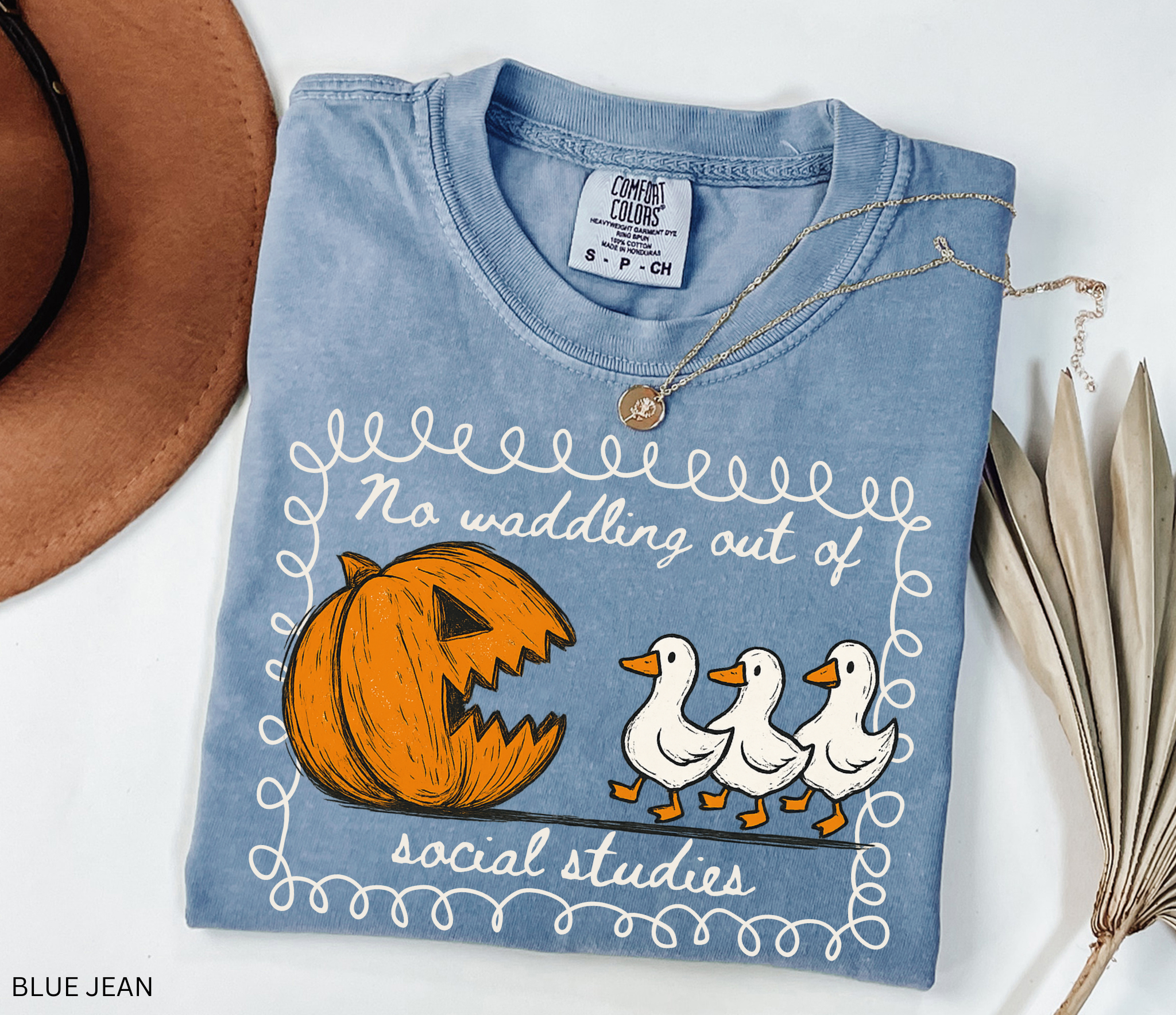 Halloween social studies teacher shirt with a pumpkin chasing geese and the phrase ‘No Waddling Out of Social Studies.’ Funny spooky season teacher tee