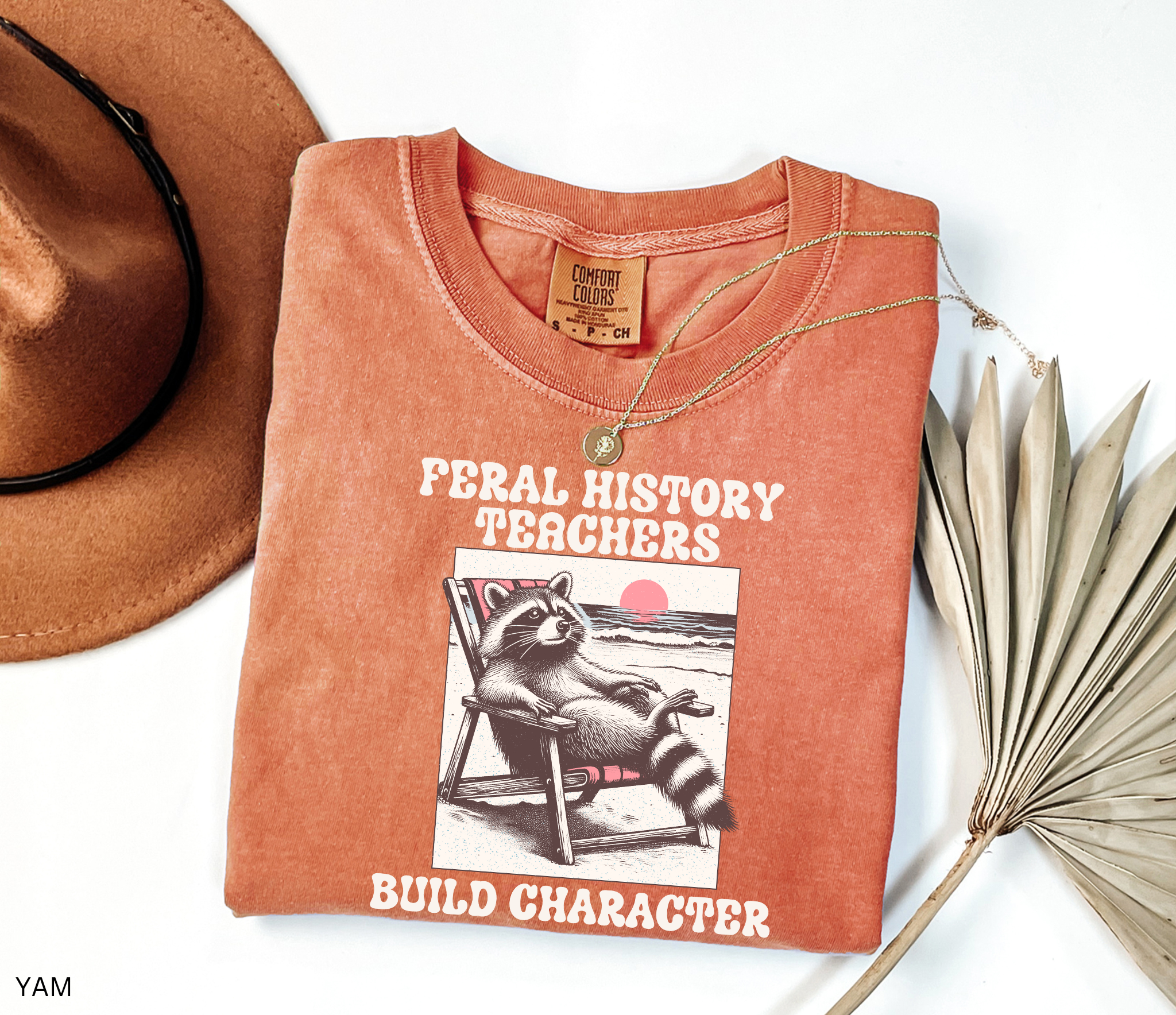 Funny history teacher shirt with a raccoon lounging in a beach chair and the phrase ‘Feral History – Teachers Build Character.’ Humorous social studies teacher tee