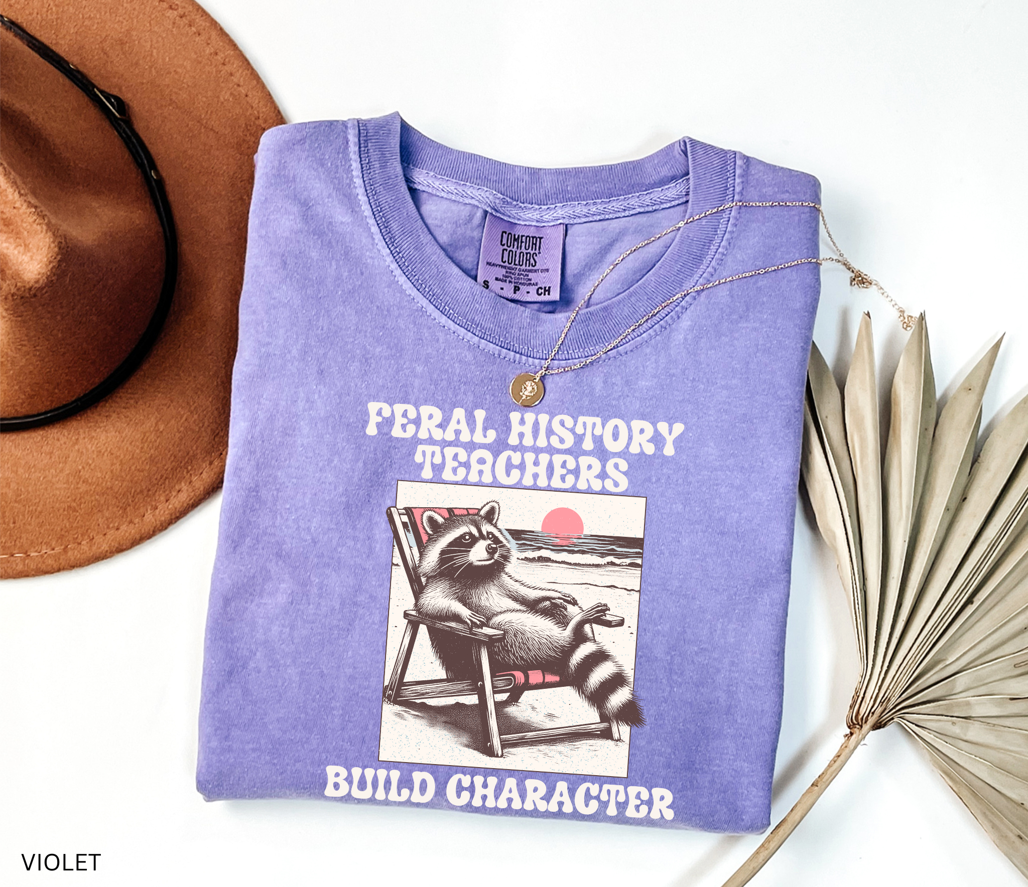 Funny history teacher shirt with a raccoon lounging in a beach chair and the phrase ‘Feral History – Teachers Build Character.’ Humorous social studies teacher tee
