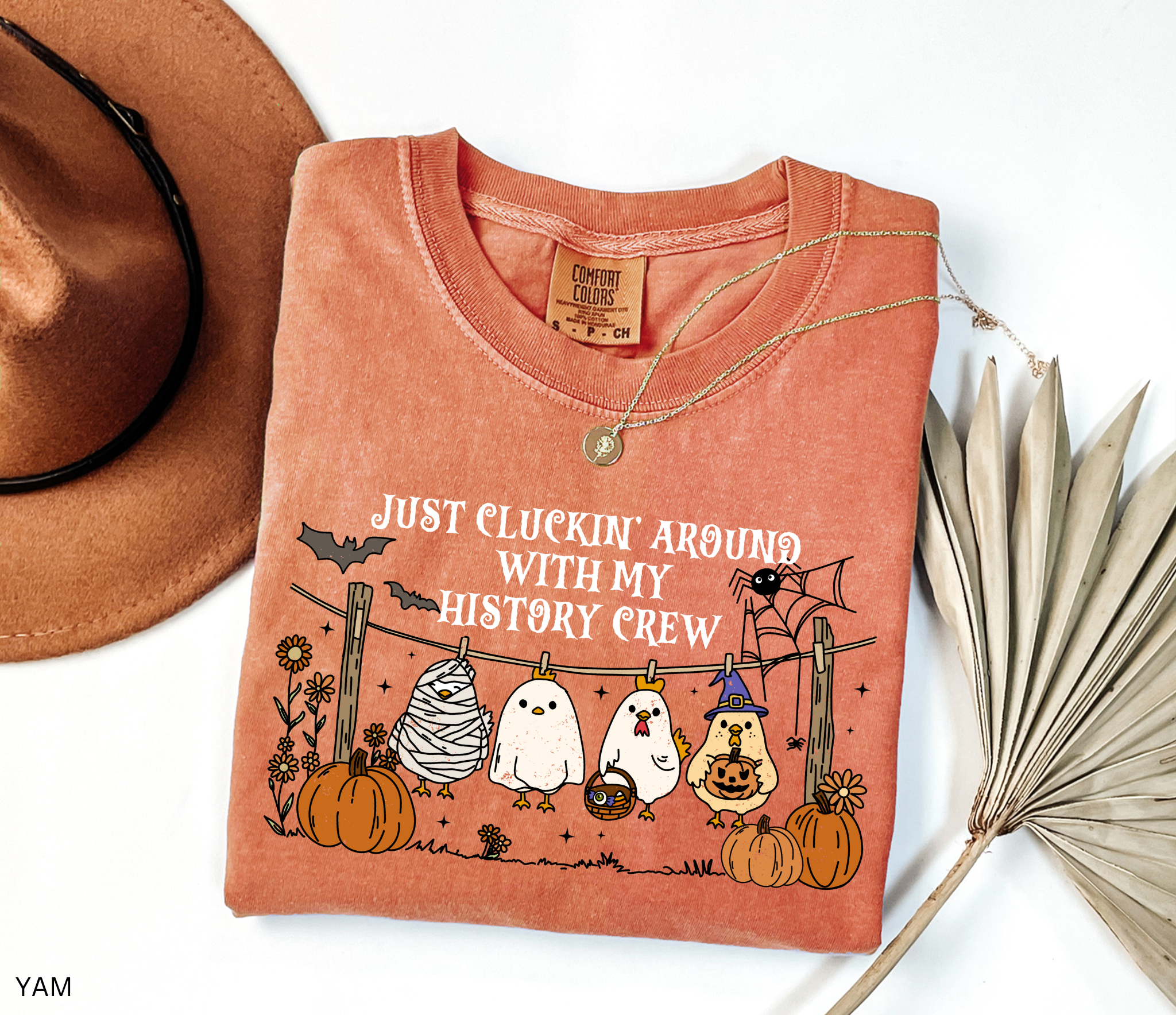 Halloween history teacher shirt with chickens in costumes on a clothesline, pumpkins, bats, and the phrase ‘Just cluckin’ around with my history crew.’ Funny group teacher shirt.