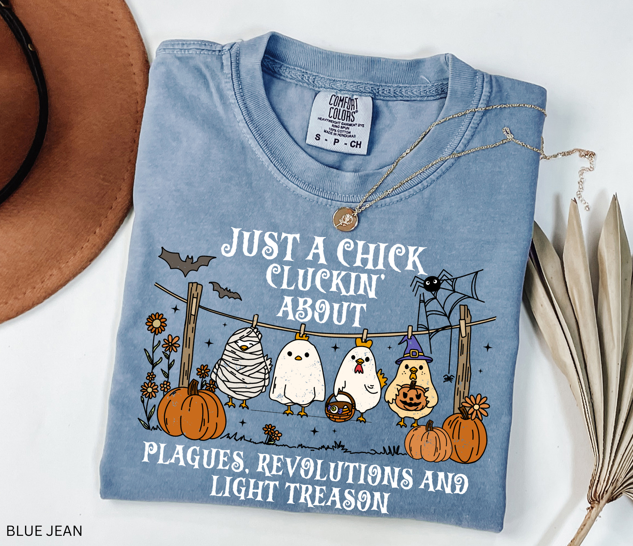 Halloween history teacher shirt with chickens in costumes, pumpkins, and text that reads ‘Just a chick cluckin’ about plagues, revolutions, and light treason.’ Funny spooky teacher tee