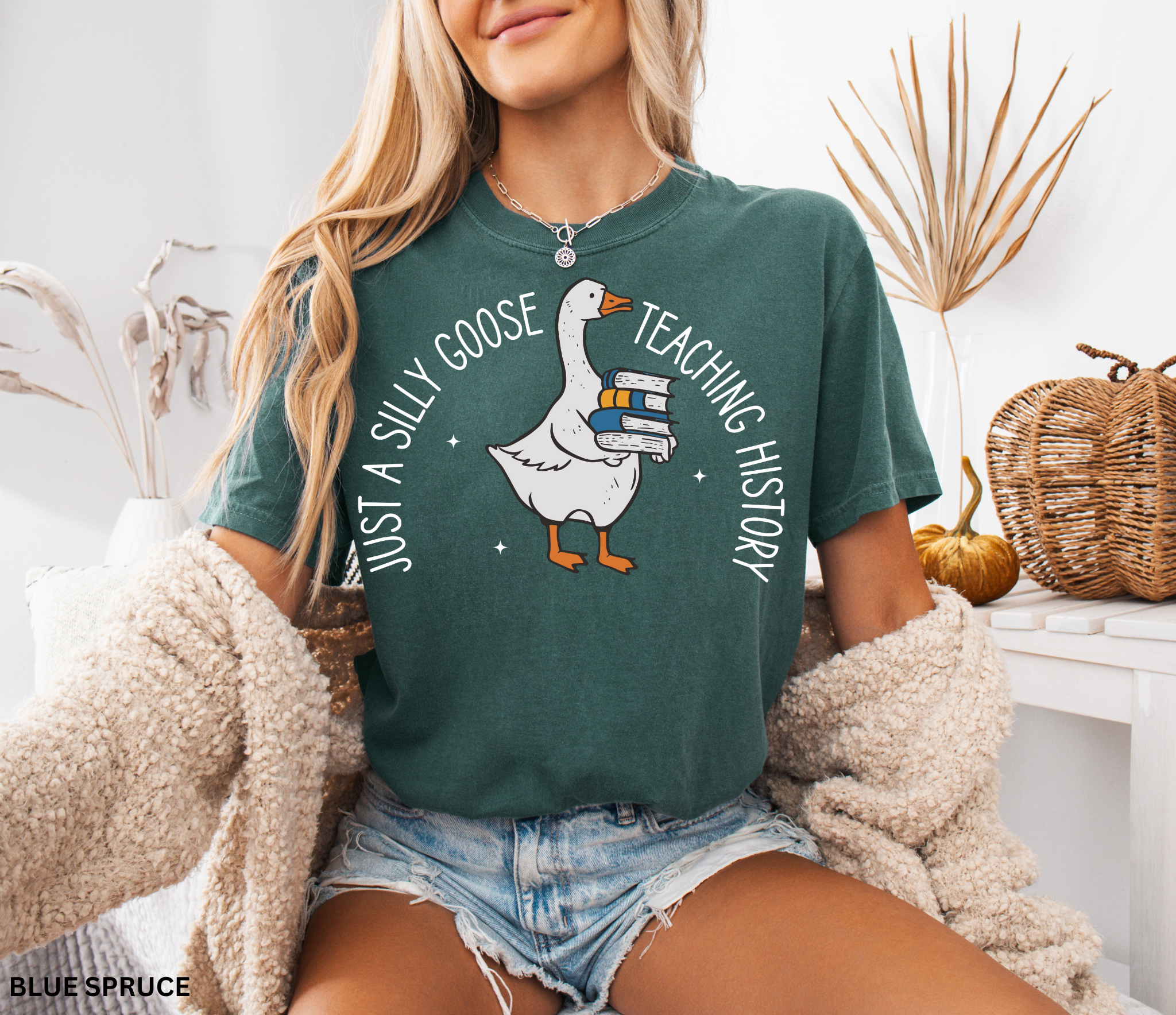 Funny teacher shirt design with a goose holding a stack of books, surrounded by stars, with the text “Just a Silly Goose Teaching History.” Perfect for history and social studies teachers.
