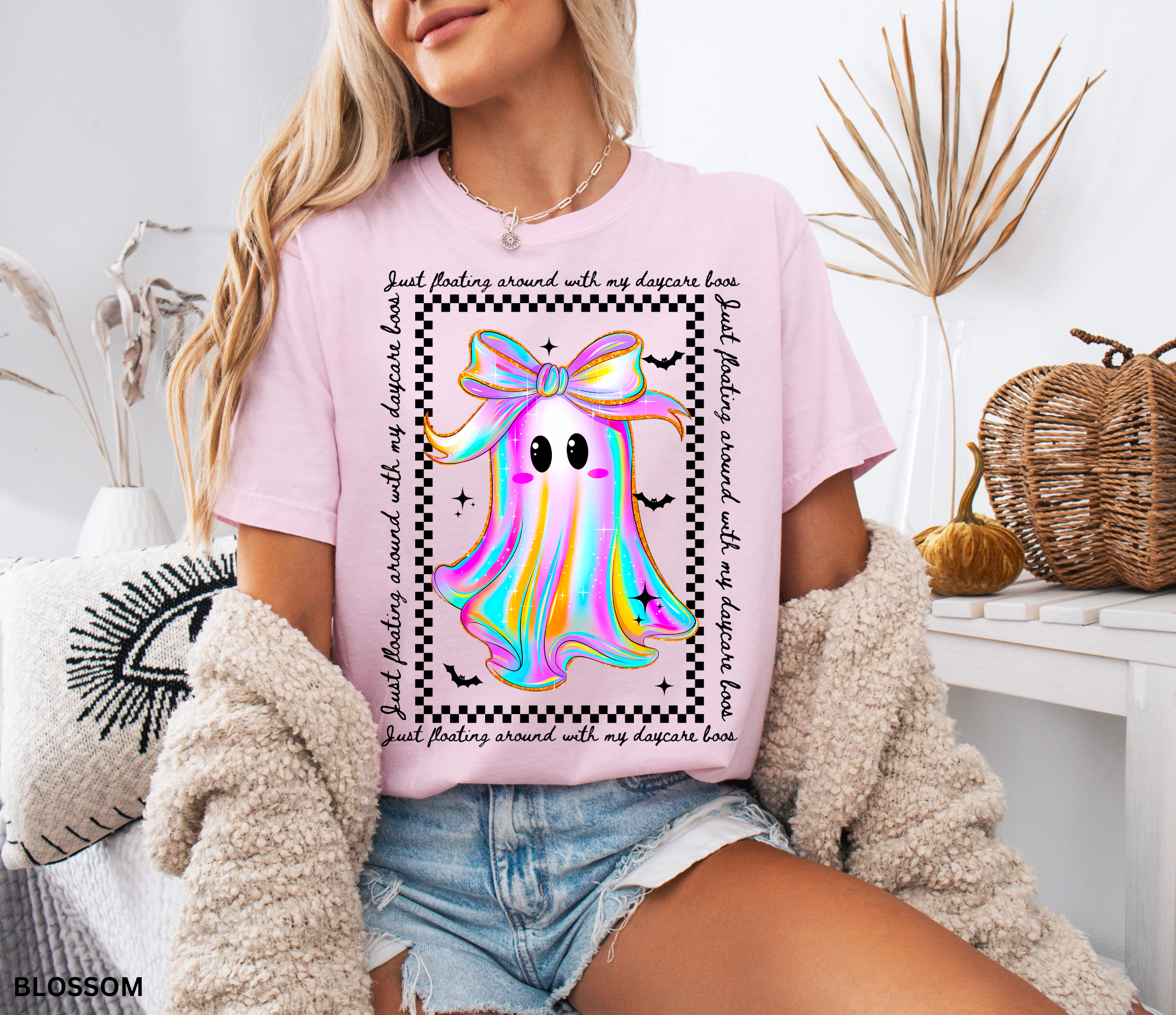 Daycare teacher Halloween shirt with rainbow ghost wearing a big bow, surrounded by stars and bats, with the phrase “Just Floating Around With My Daycare Boos.” Cute spooky season tee for childcare workers.