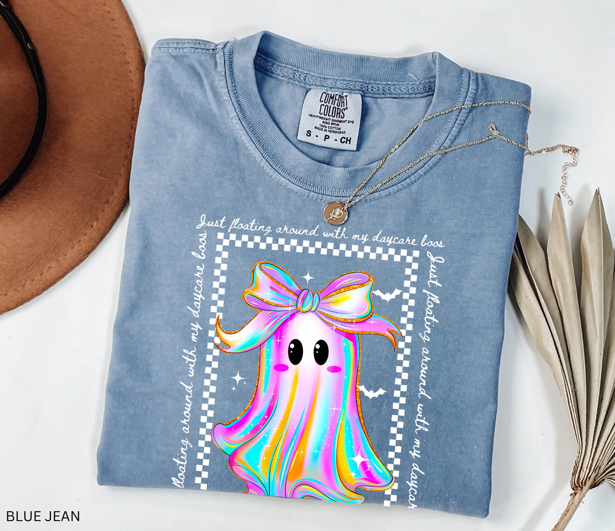 Daycare teacher Halloween shirt with rainbow ghost wearing a big bow, surrounded by stars and bats, with the phrase “Just Floating Around With My Daycare Boos.” Cute spooky season tee for childcare workers.