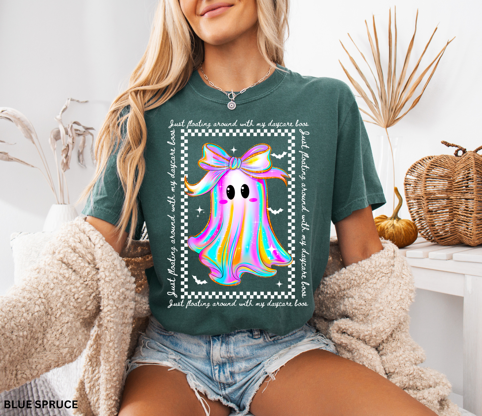 Daycare teacher Halloween shirt with rainbow ghost wearing a big bow, surrounded by stars and bats, with the phrase “Just Floating Around With My Daycare Boos.” Cute spooky season tee for childcare workers.