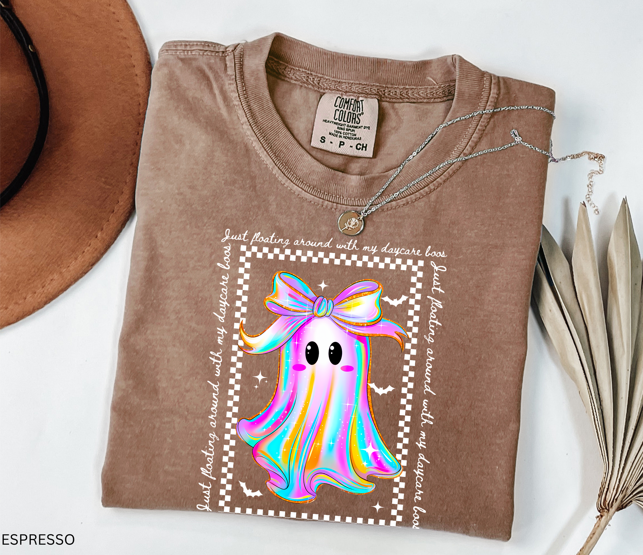 Daycare teacher Halloween shirt with rainbow ghost wearing a big bow, surrounded by stars and bats, with the phrase “Just Floating Around With My Daycare Boos.” Cute spooky season tee for childcare workers.