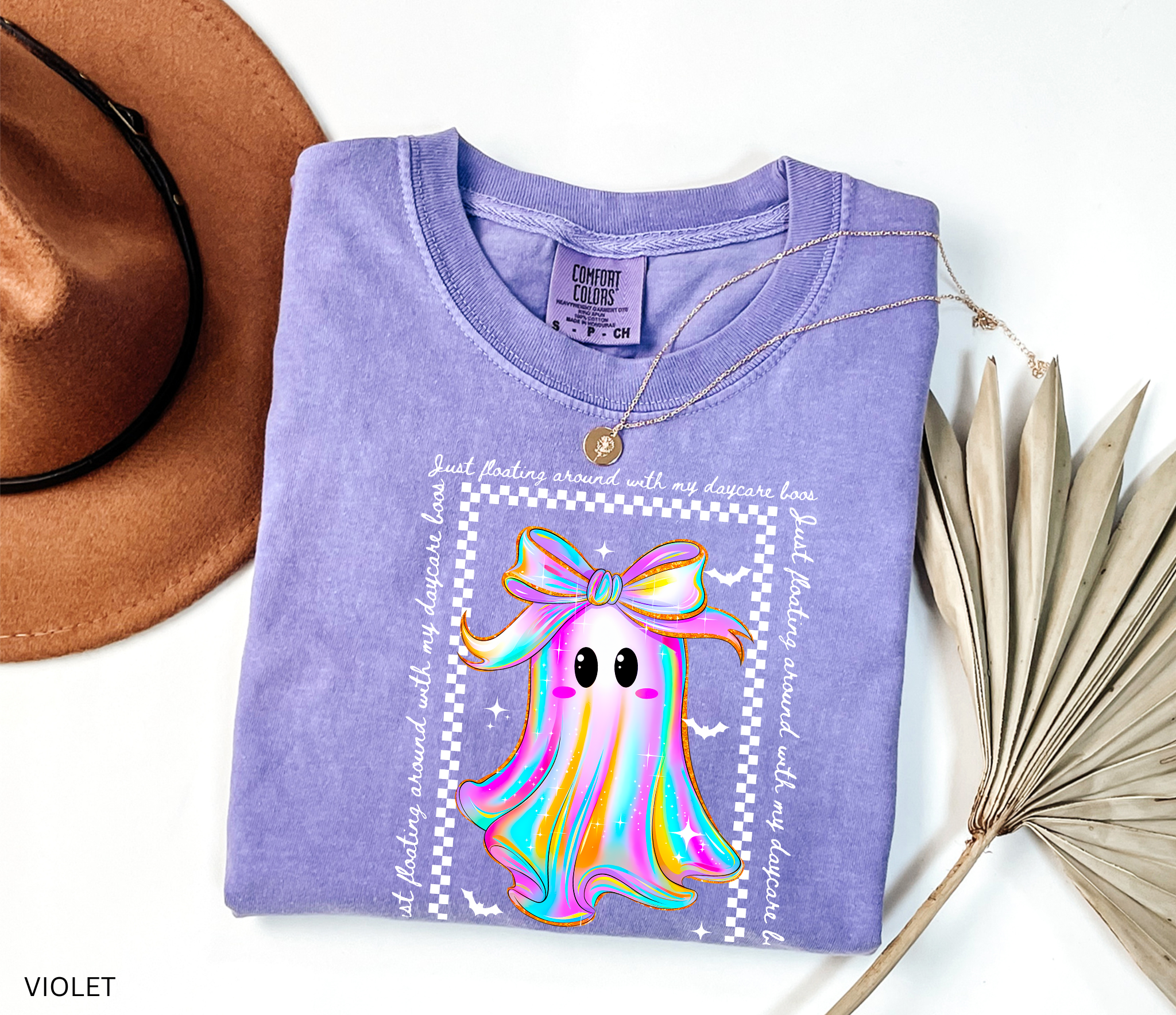 Daycare teacher Halloween shirt with rainbow ghost wearing a big bow, surrounded by stars and bats, with the phrase “Just Floating Around With My Daycare Boos.” Cute spooky season tee for childcare workers.