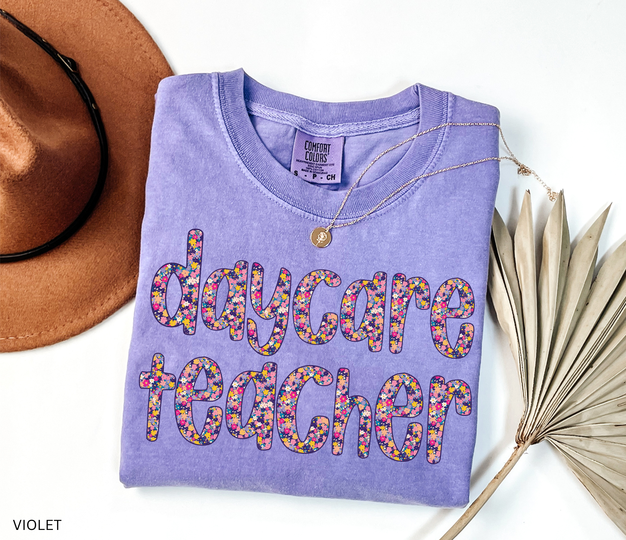 Daycare teacher shirt with bold floral text design in bright colors, fun and cheerful tee for childcare workers and preschool teachers.
