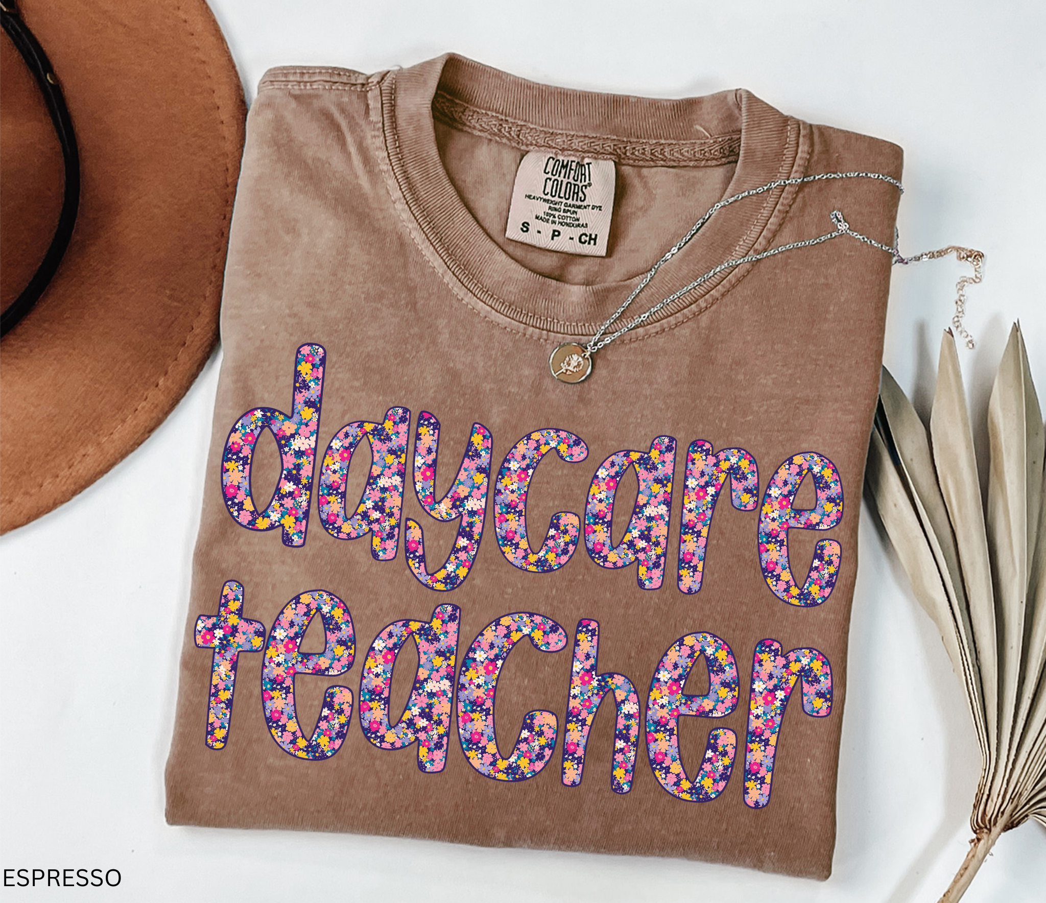 Daycare teacher shirt with bold floral text design in bright colors, fun and cheerful tee for childcare workers and preschool teachers.
