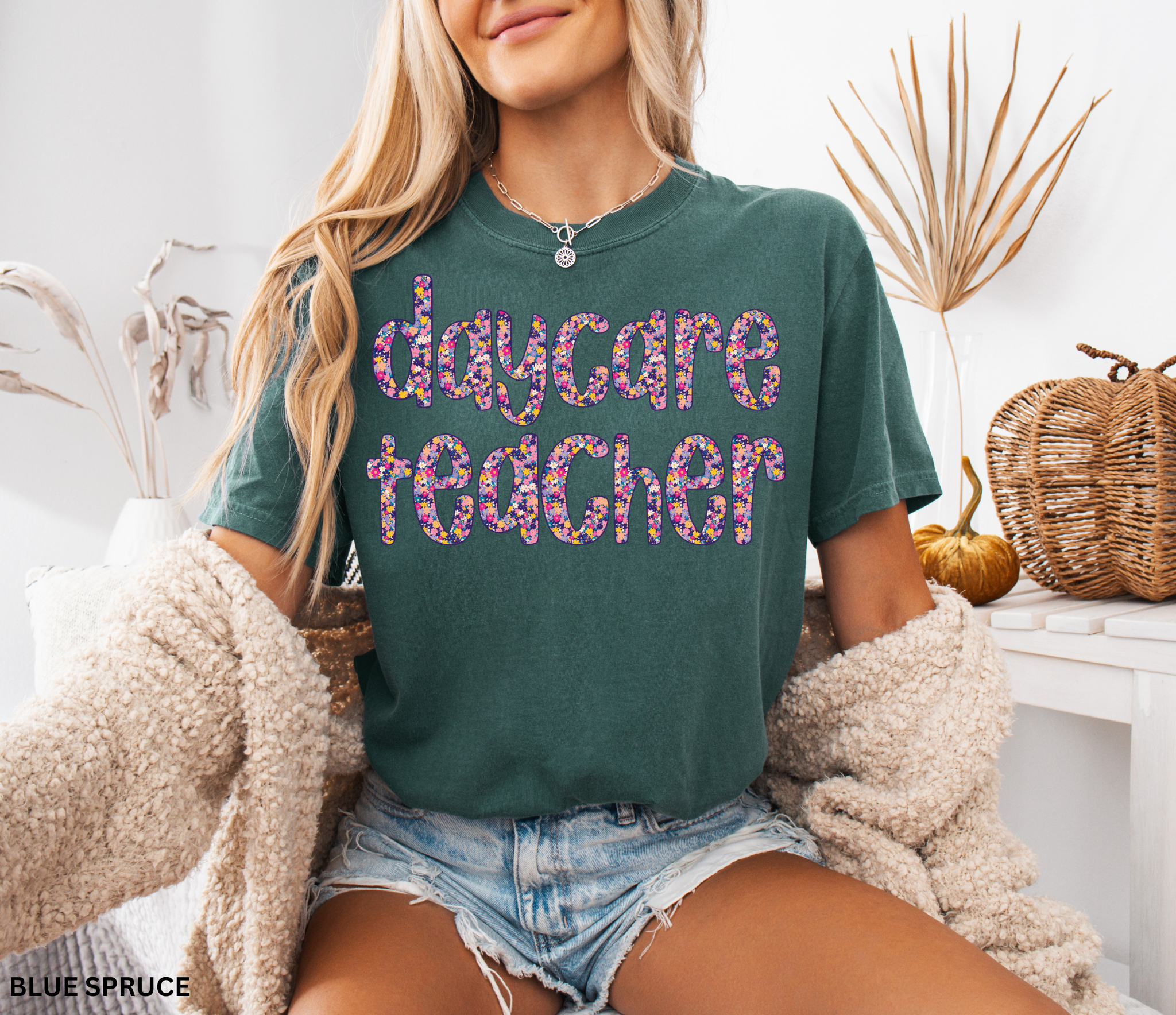 Daycare teacher shirt with bold floral text design in bright colors, fun and cheerful tee for childcare workers and preschool teachers.