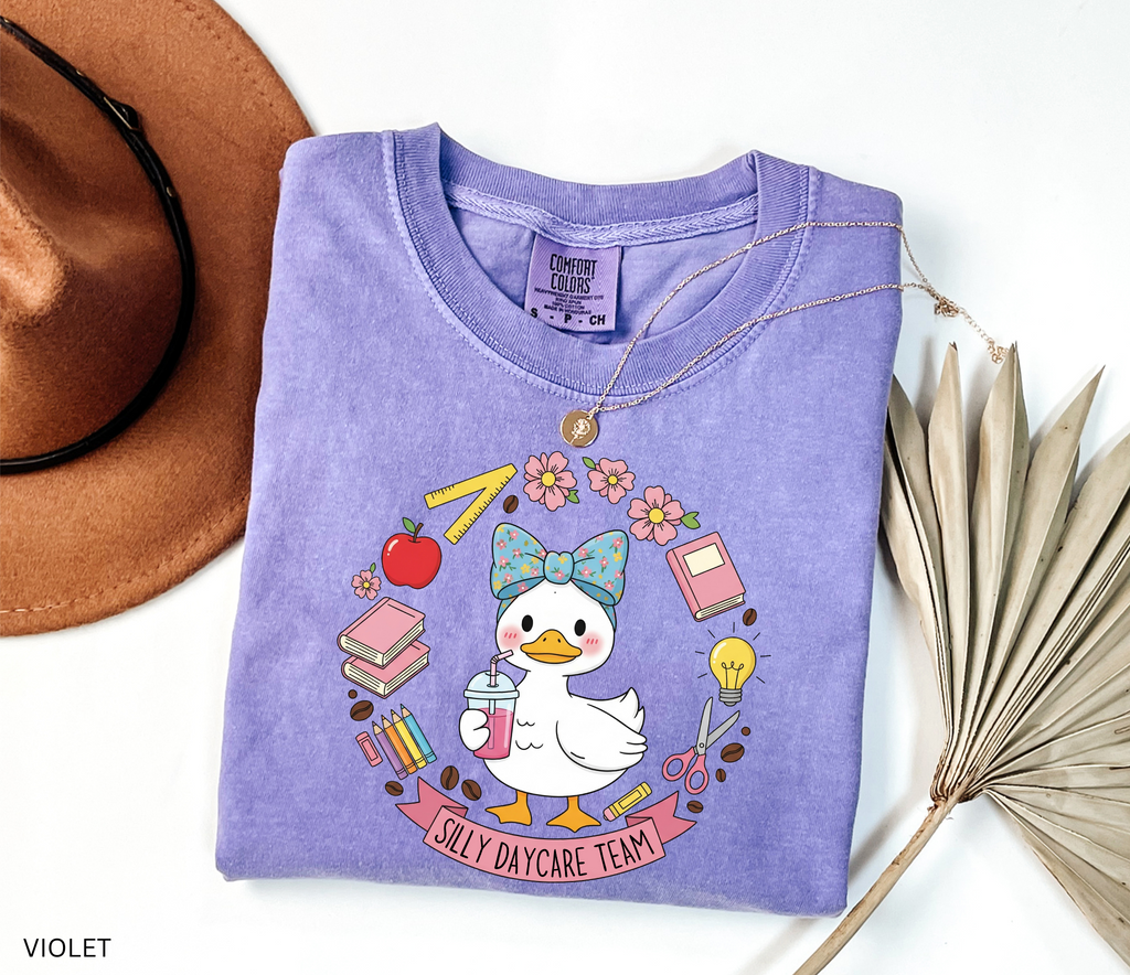Cute goose in a floral bow holding a drink, surrounded by books, pencils, apple, ruler, flowers, scissors, and lightbulb with banner reading “Silly Daycare Team.”