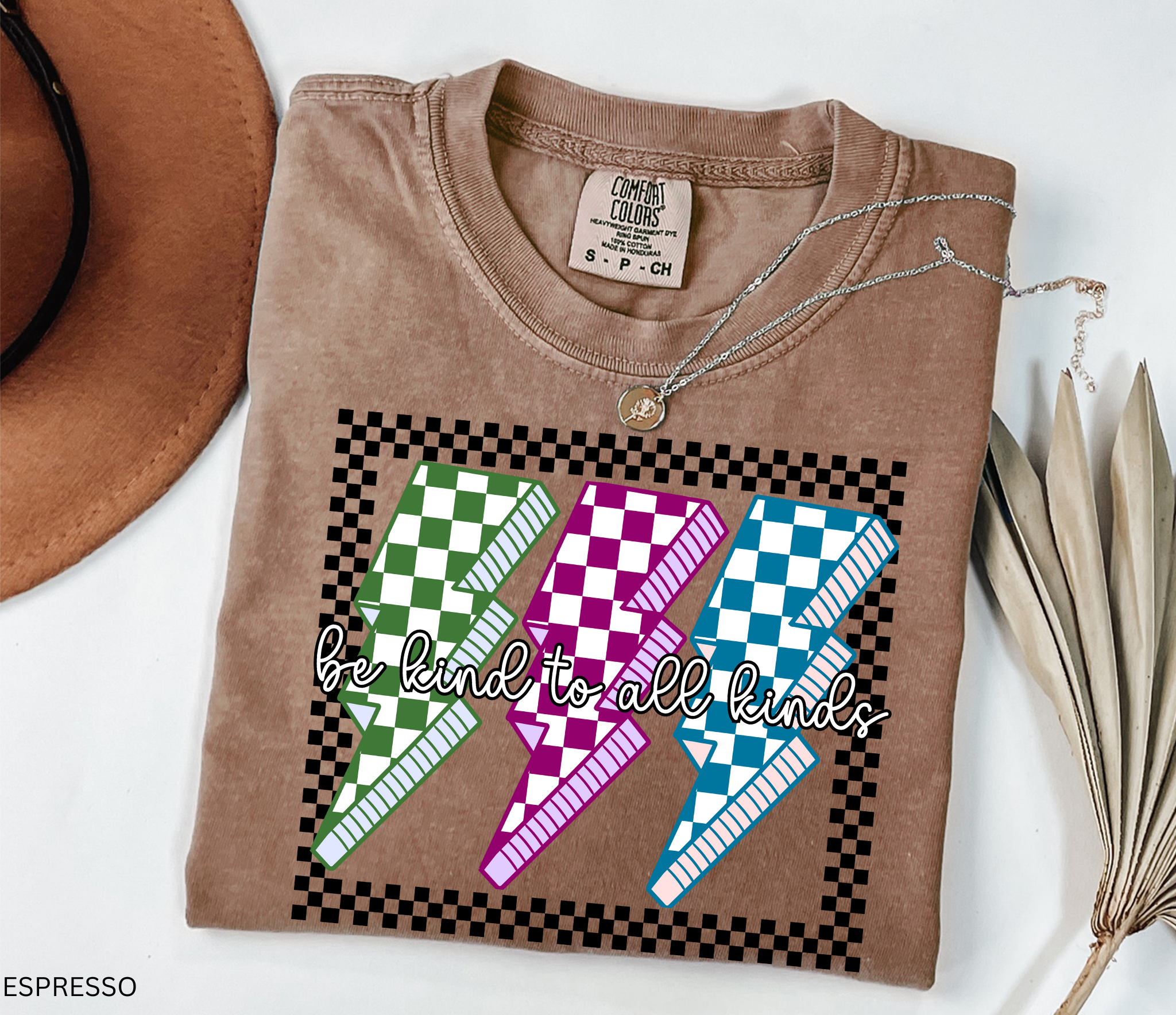 Checkerboard lightning bolt “Be Kind to All Kinds” shirt in retro green, pink, and blue design – inclusive teacher graphic tee.